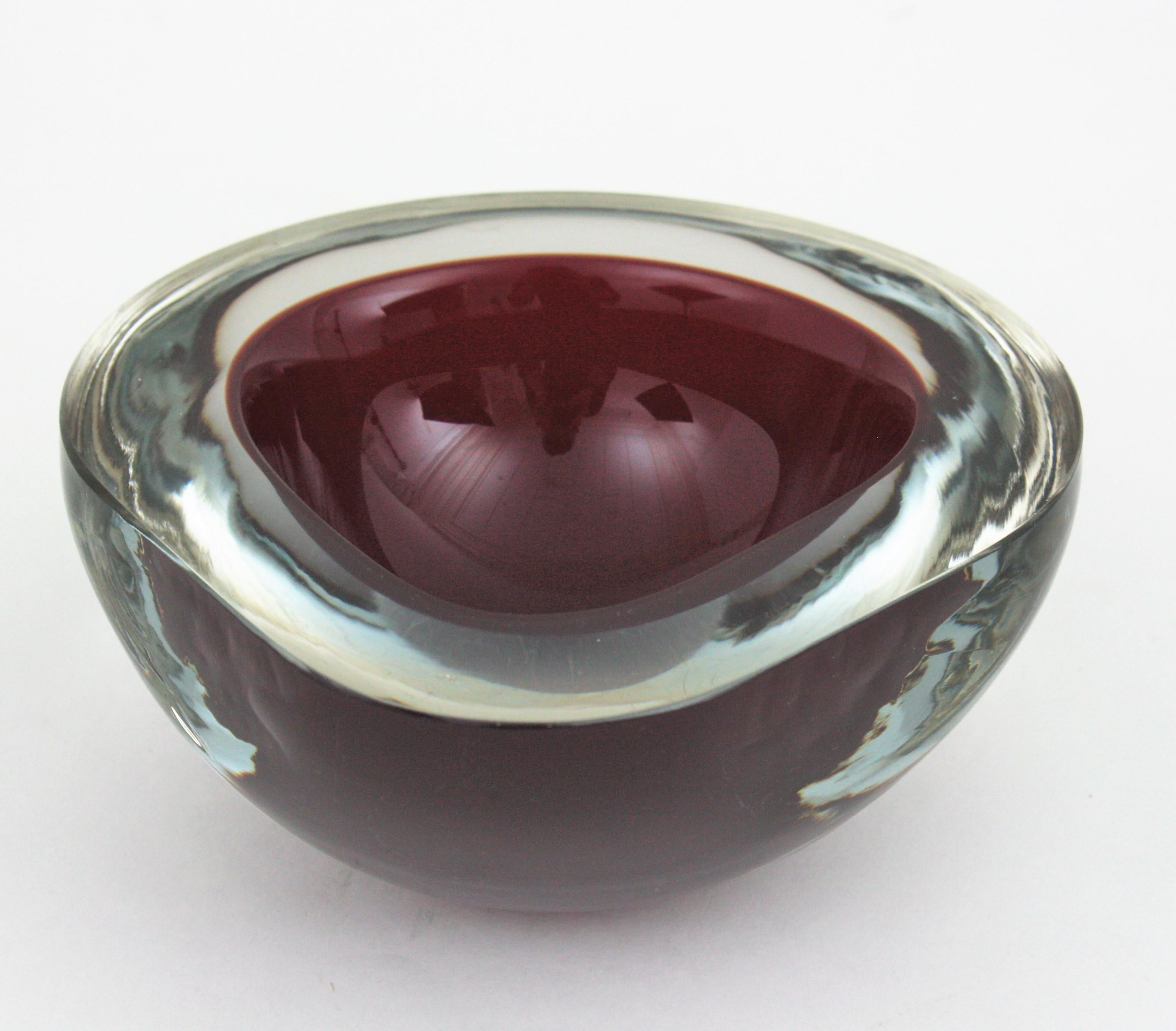Hand blown Murano Sommerso triangle geode bowl in garnet glass. Italy, 1960s.
This geode bowl in shades of Burgundy glass summerged into clear glass using the 