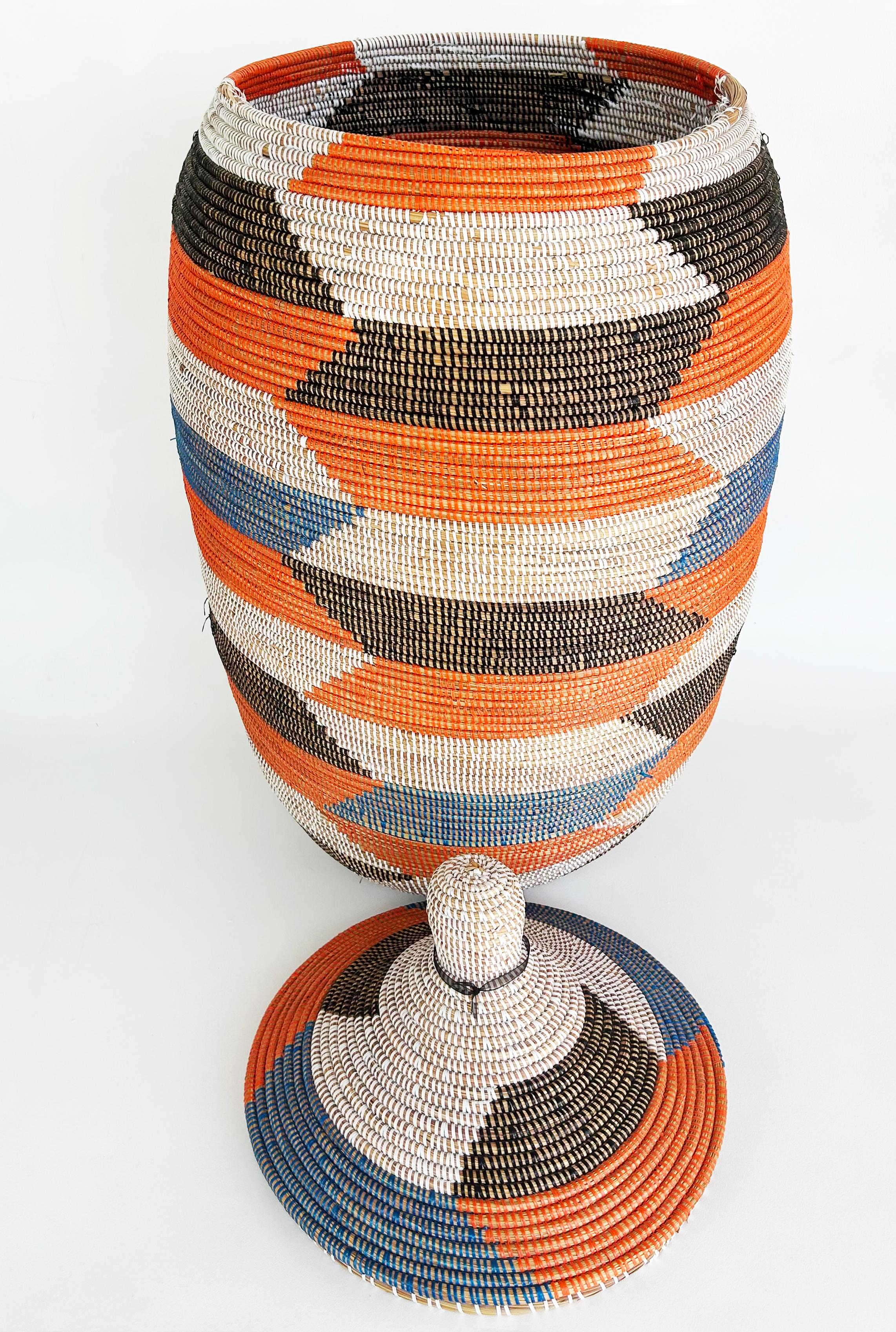 Large Senegalese Hand-Woven Basket/Hamper with Top

Offered for sale is a large and colorful geometrically designed hand woven  basked from Senegal. The basket is made from coiled reed that has been wrapped in orange, blue, black and white acrylic