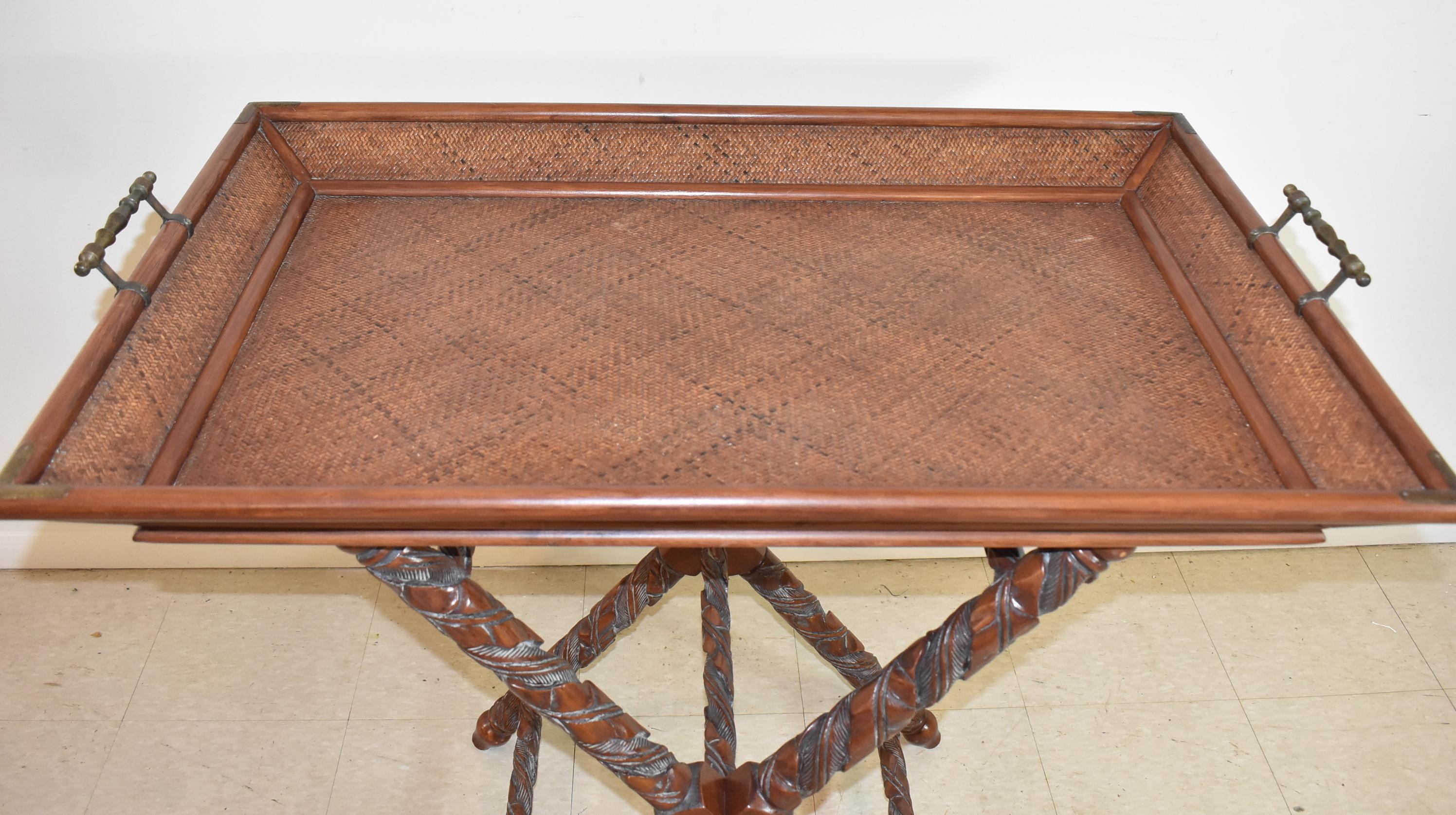 Large serving tray table on a carved mahogany X base with cross stretchers. Tray features brass handles and a basket weave interior. Excellent condition. 38