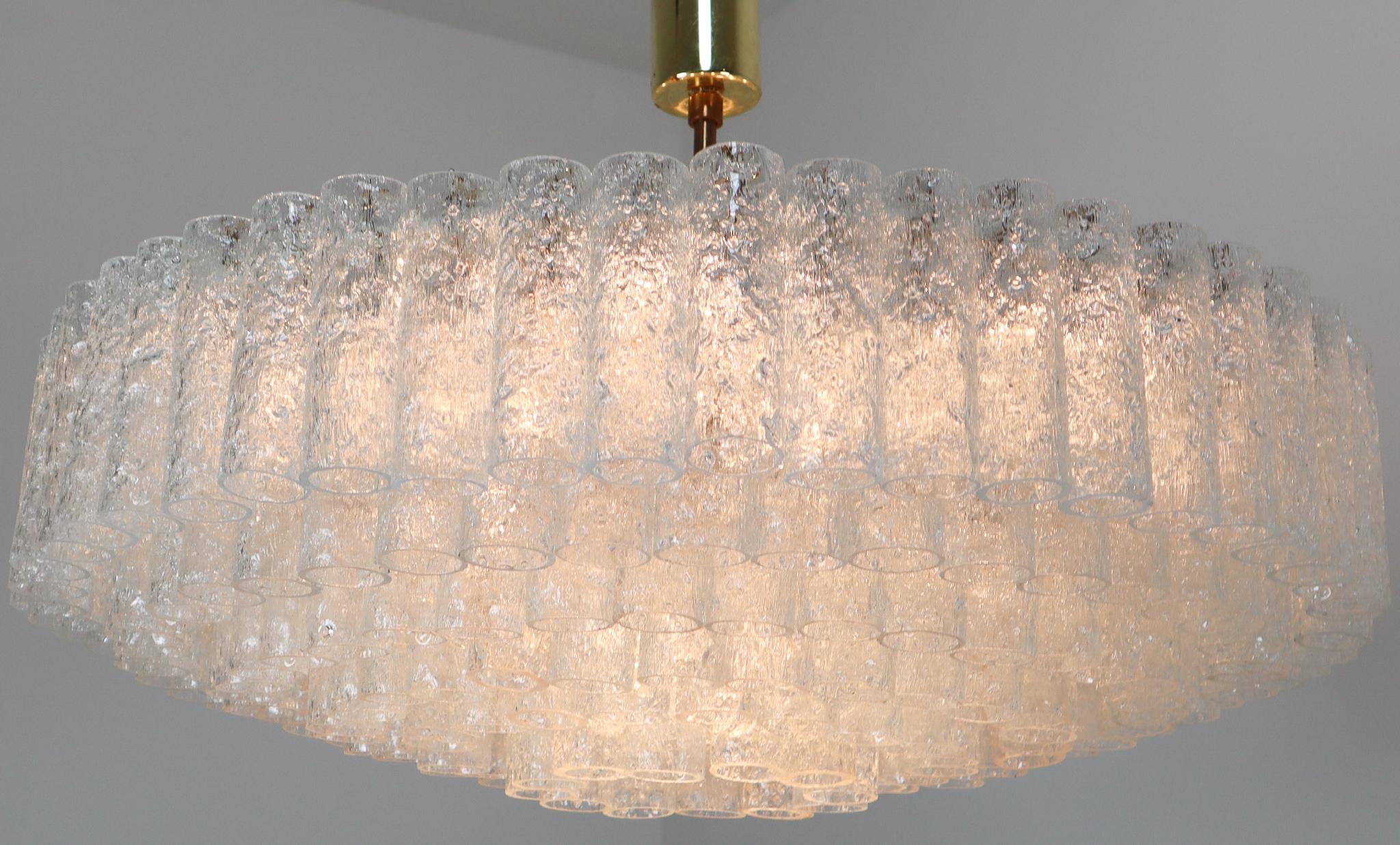(XL-size) Gorgeous, 1950s midcentury chandeliers was designed by Doria Leuchten, Germany. It features multi-tiered layers of textured ice glass tubes connected to a circular brushed brass frame. The flush mount with almost 200 glass tubes requires