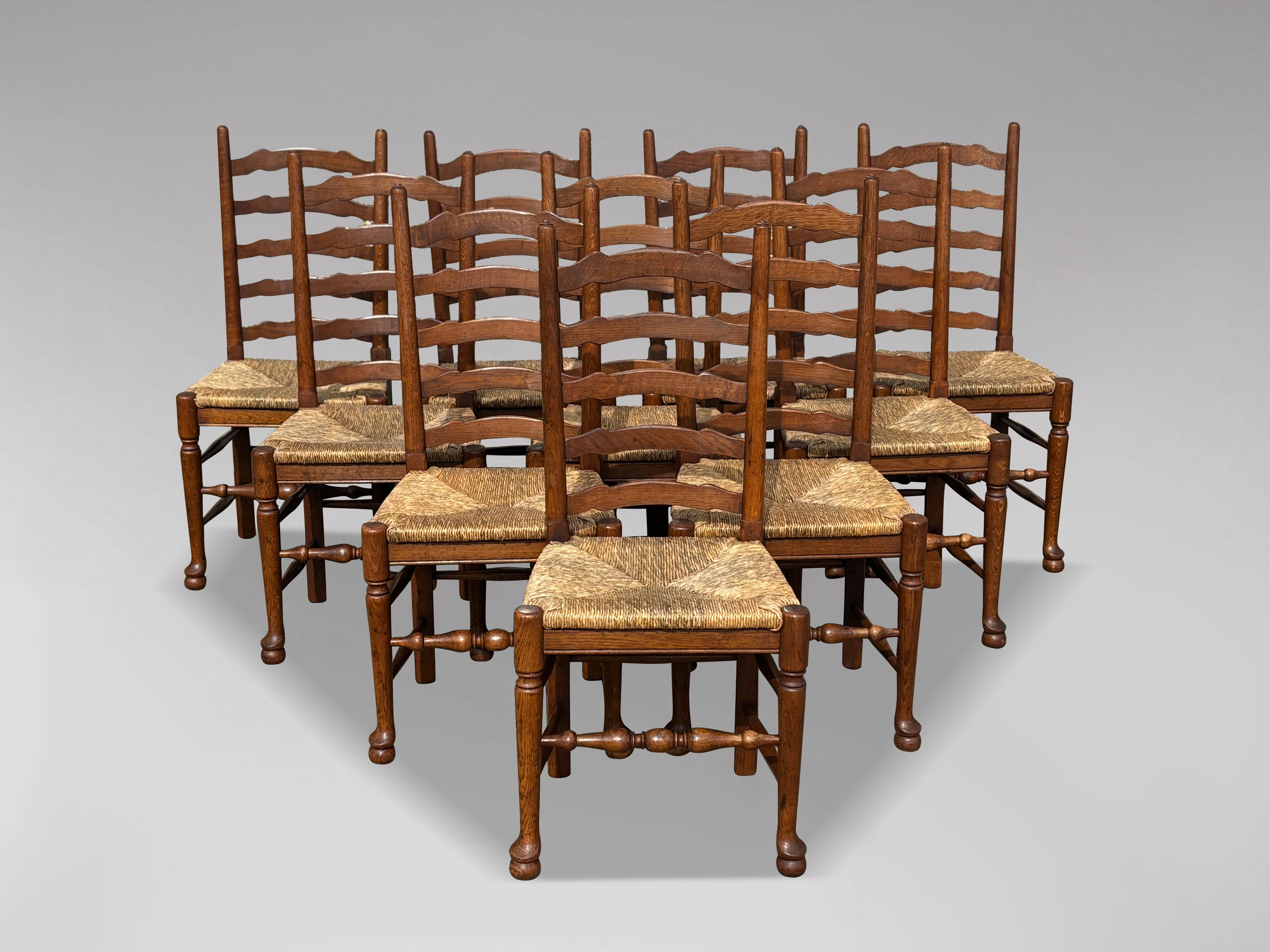 A matching set of 10 solid oak Lancashire ladder back rush seated dining chairs in the Georgian style. All in very good condition believed to be made around the early 20th century. These gorgeous dining chairs feature a lovely original light oak