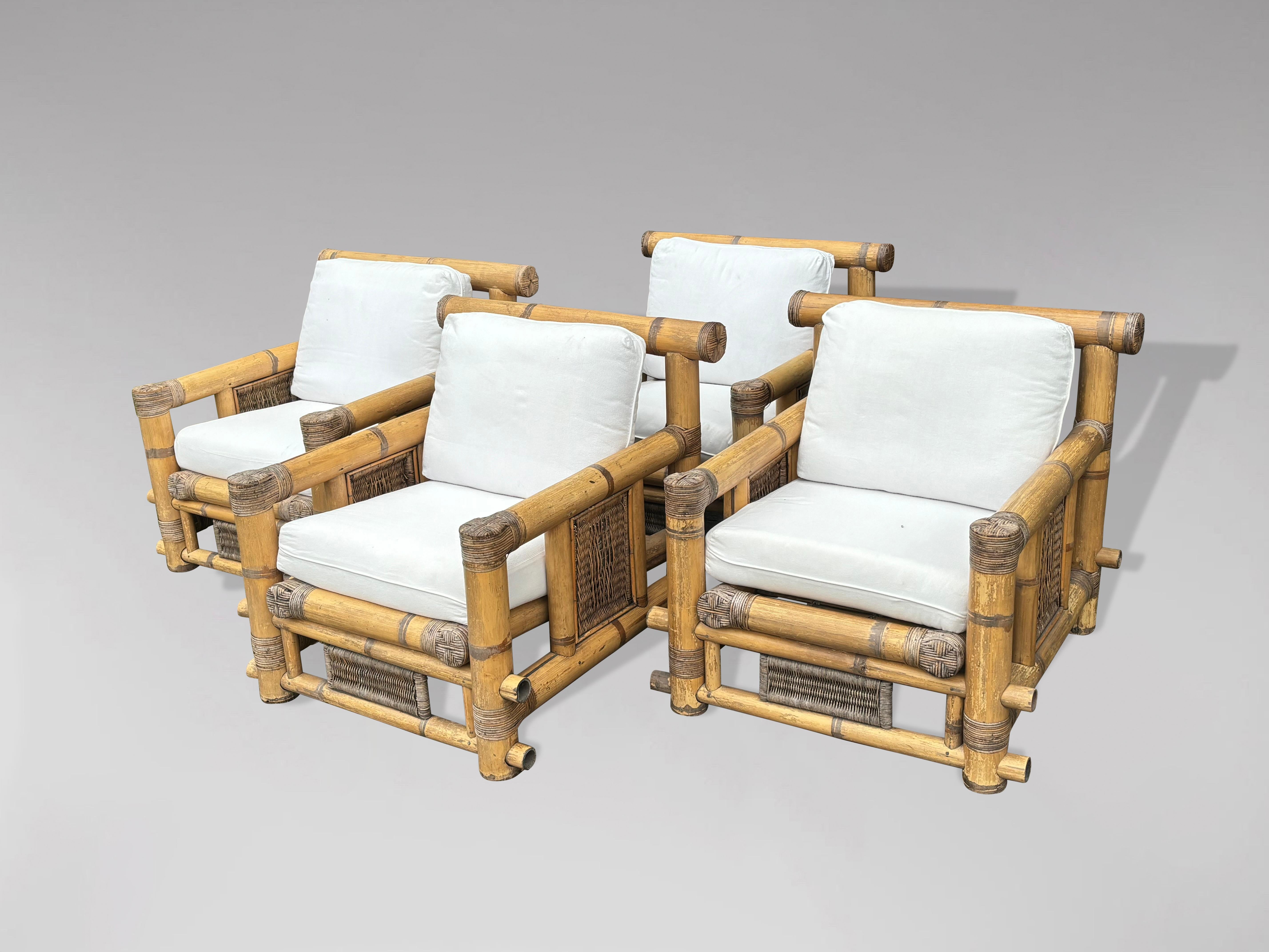 A set of 4 large club lounge coastal armchairs, designed by Budji Layug, circa 1980. Very large, mature stalks of cut bamboo cleverly constructed to execute an over-scale armchair with beautiful contrasting cane and rattan accents. Each armchair