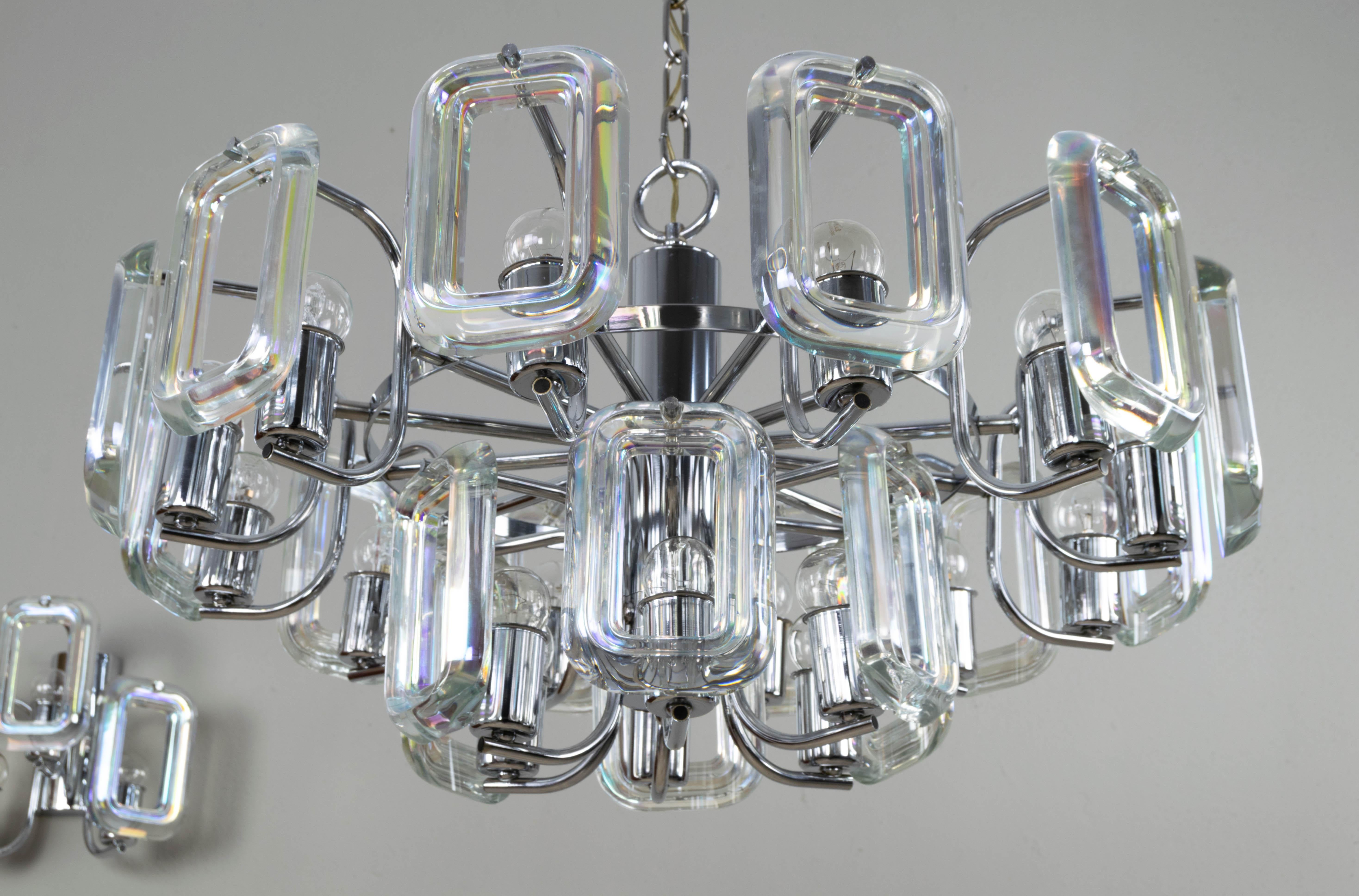 This elegant and exclusive Italian set of chandelier and sconces of the 1970s is composed of iridicentes rectangular crystals in the form of links and steel.
They have a spectacular design hard to find.
The two sconces are composed of a chromed