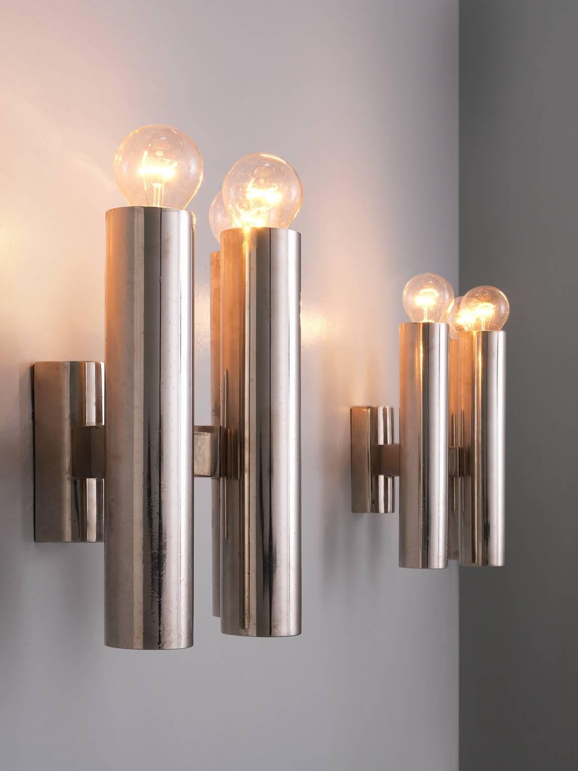 Wall lights, chromed metal, Europe, 1970s.

Large set of wall lights. Each light consist of three cylindrical chrome candle holder inspired tubes, which are held by a chrome frame. The alignment of these three lights are formed as if in a
