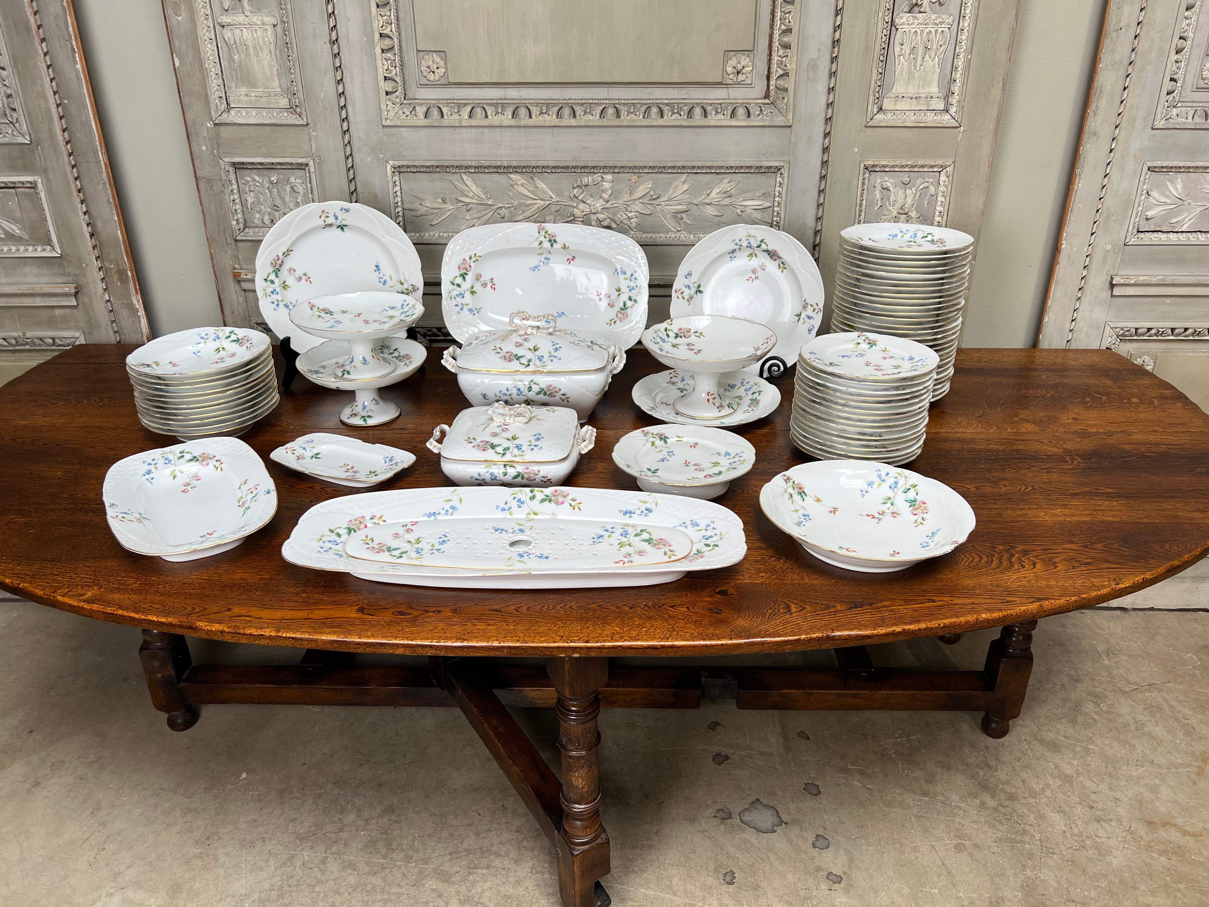 Grand service de table en porcelaine française de style Louis XV à fond blanc avec des motifs floraux roses et bleus et des bordures dorées.  Cet ensemble se compose de 
26 assiettes de 9