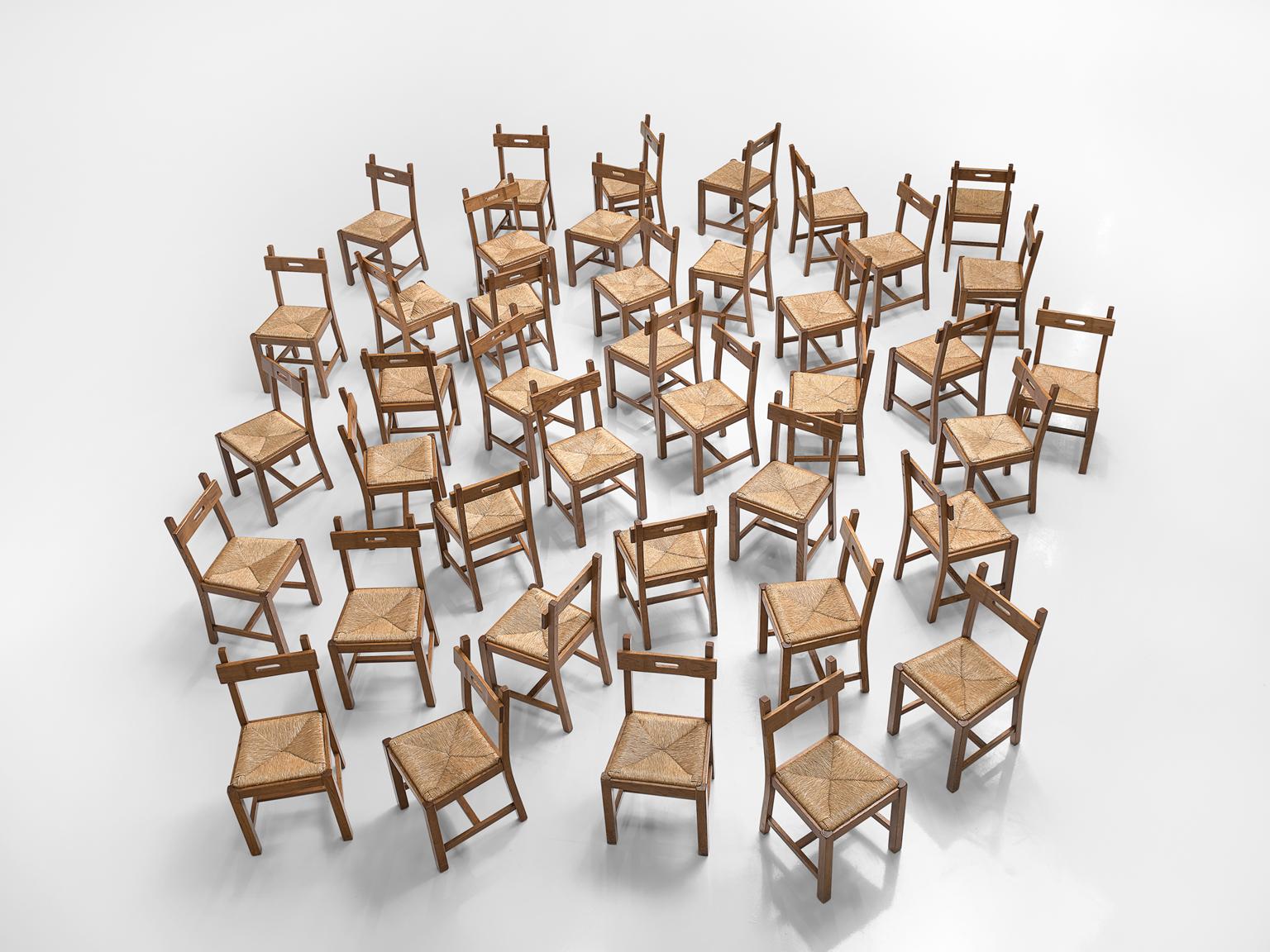 Set of 40 chairs, oak, Belgium, 1960s.

Large set of chairs are executed in oak which has gained a rich patina over time and a seat of cord. The chairs have a very solid and geometric backrest. The chairs are both functional and clear in their