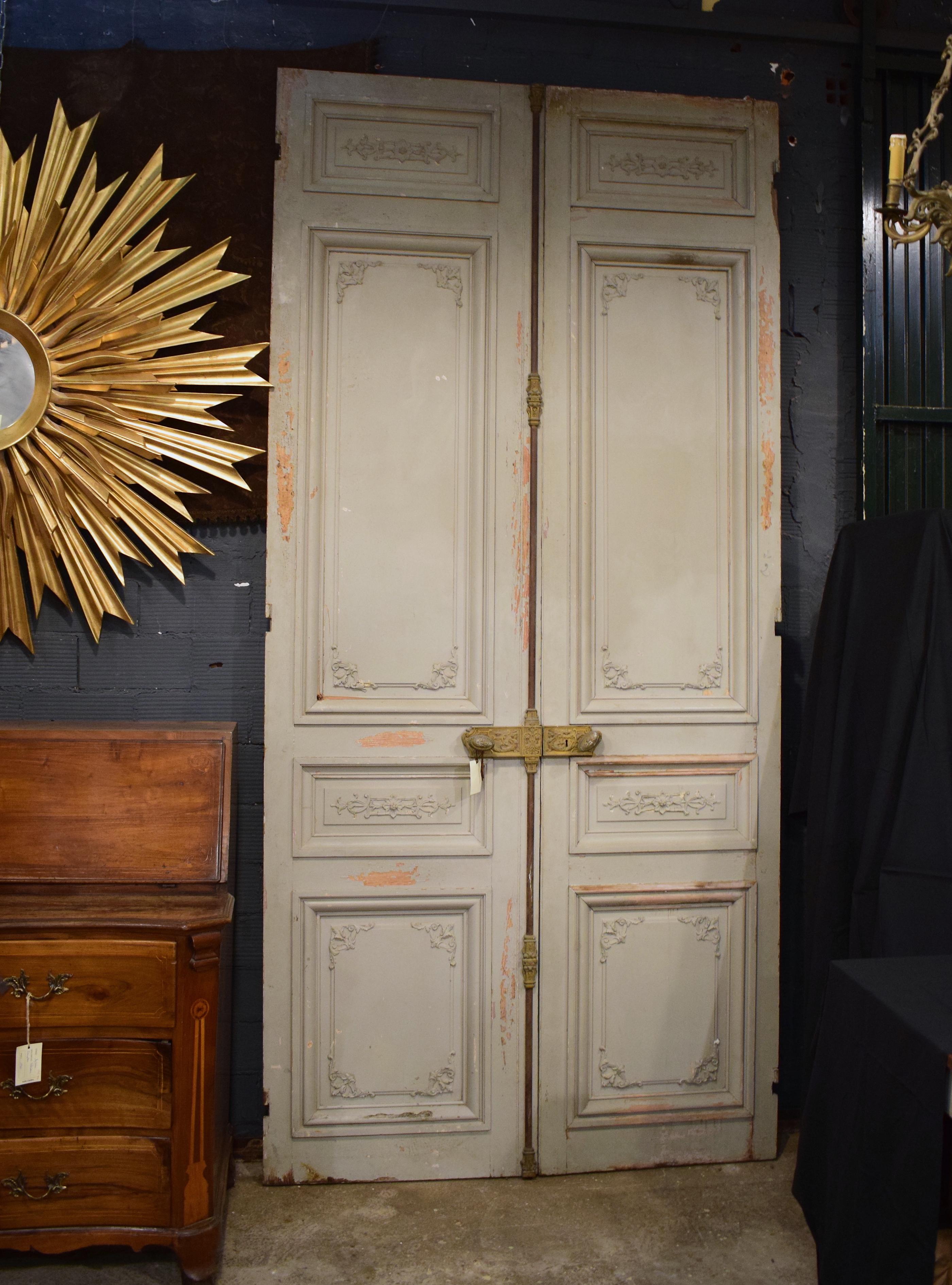 This magnificent set of large exterior double doors are French and from the Napoleon III period. Each panel has hand crafted structural detail of rosettes and flowers carved into them. The doors have their original brass lock intact which has