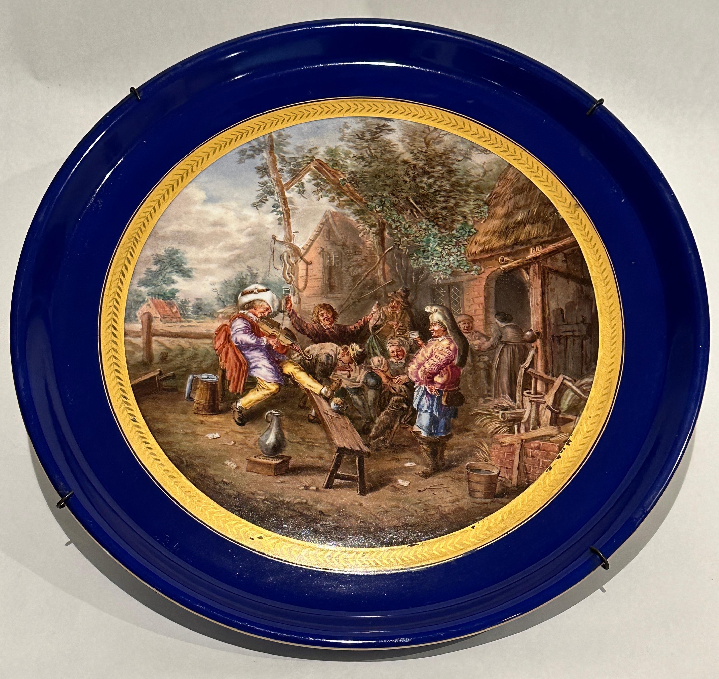 This large French porcelain charger, in the Sèvres style, is intricately painted with a period courtyard scene, set in the yard of a house with family gathering in celebration. Father figure playing a stringed instrument, in the presence of other