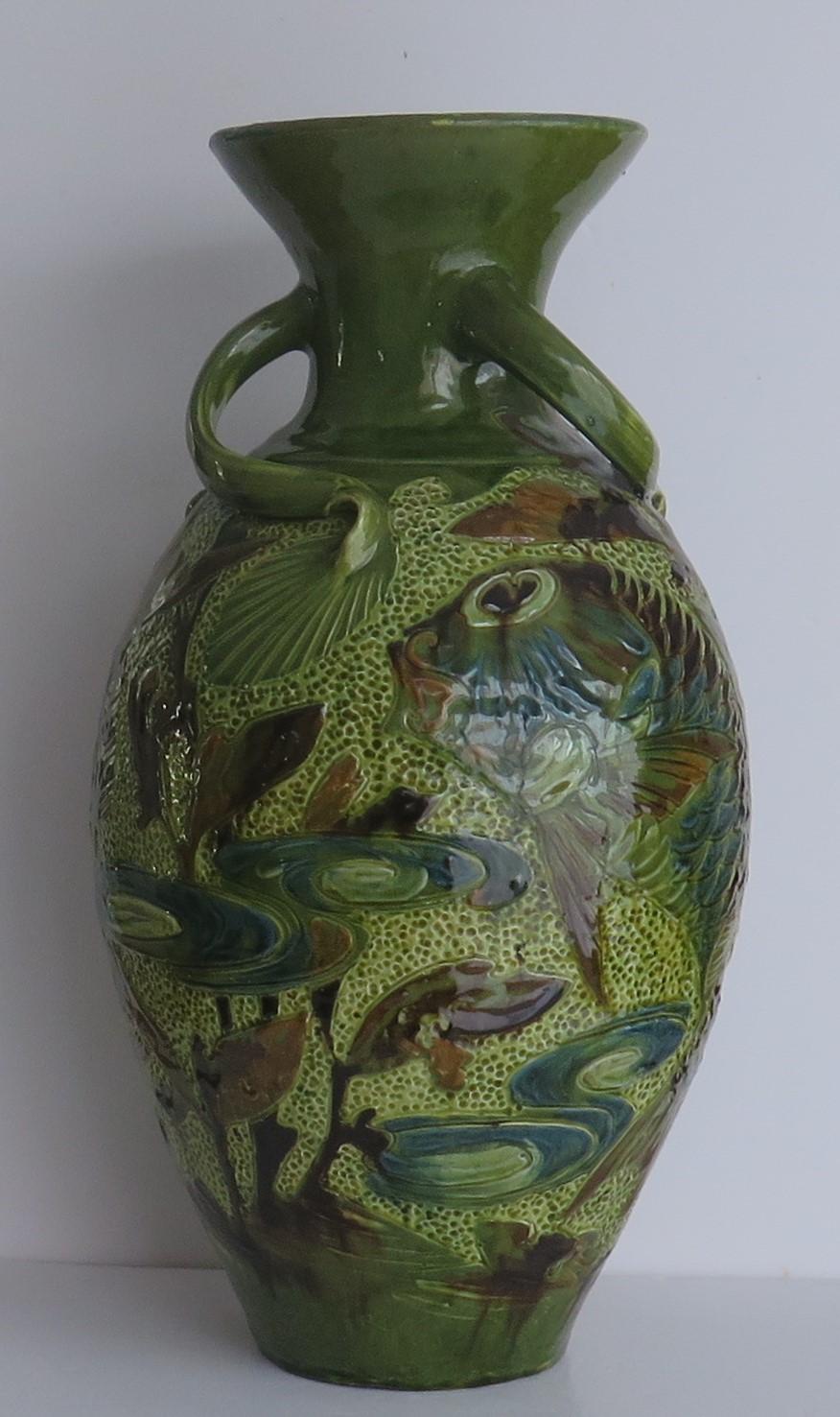This is a large impressive Art Pottery Vase, with three angular handles, all hand modelled using the Sgraffito method, with Fish decoration, hand made by W L BARON of Barnstaple, Devon, England and dating to the Edwardian period, 1909.

This vase