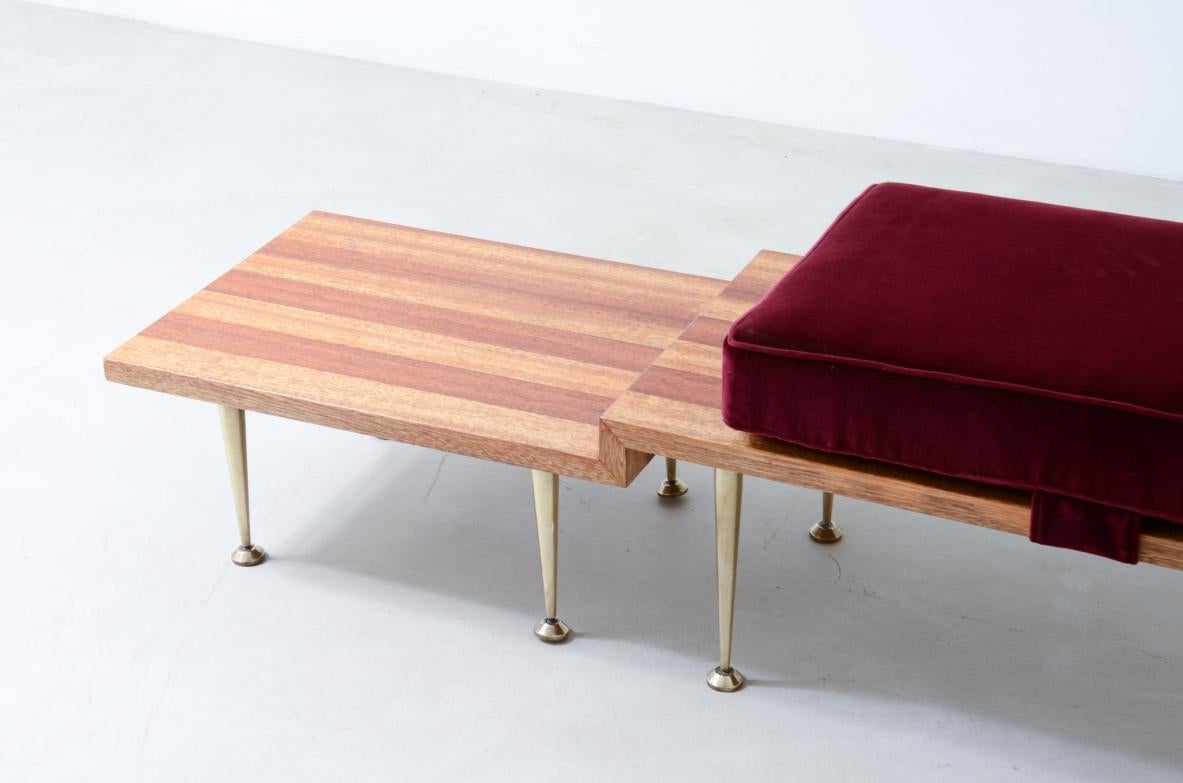 Large shaped wooden bench with eight turned brass feet and velvet-covered cushions.

Italian manufacture from the 1950s

