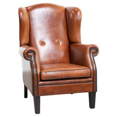 Large sheepskin wingback chair with black piping and decorative nails