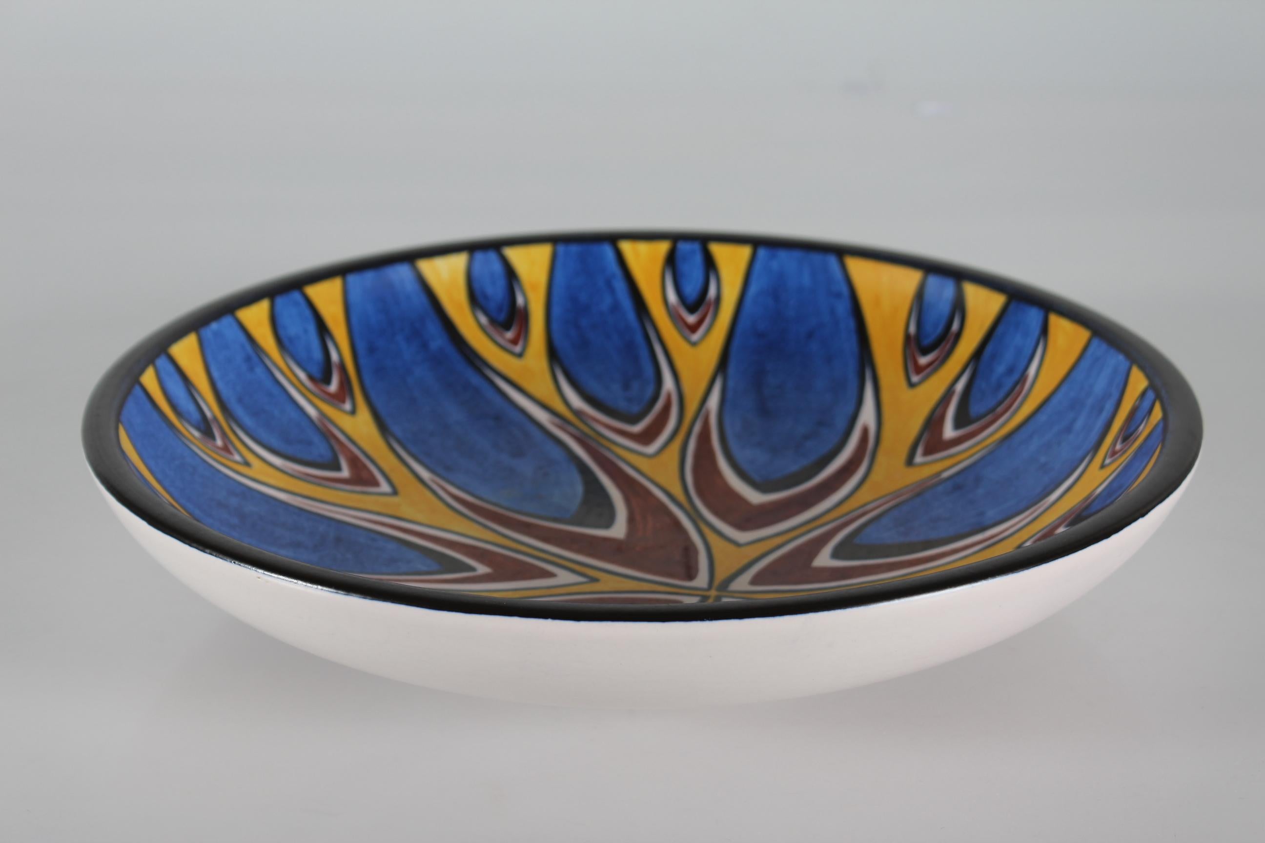 Large low ceramic bowl by Søholm Denmark.
This bowl has a graphic pattern in bright colors of blue, yellow, brown and black. The glaze is matte, the outside of the bowl has white glaze and the rim is black.

The bowl is signed Søholm on the