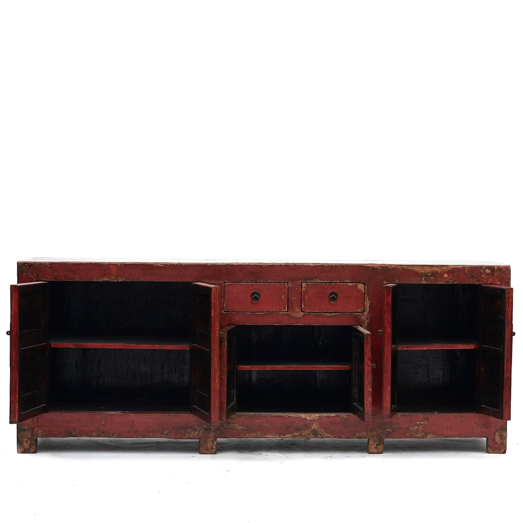 Large sideboard (W: 237,5) with three pairs of doors, above the doors in the middle a pair of drawers. The sideboard has a original thick red lacquer on the front/ top and black lacquer on the sides.
The natural wear gives a charm and character,