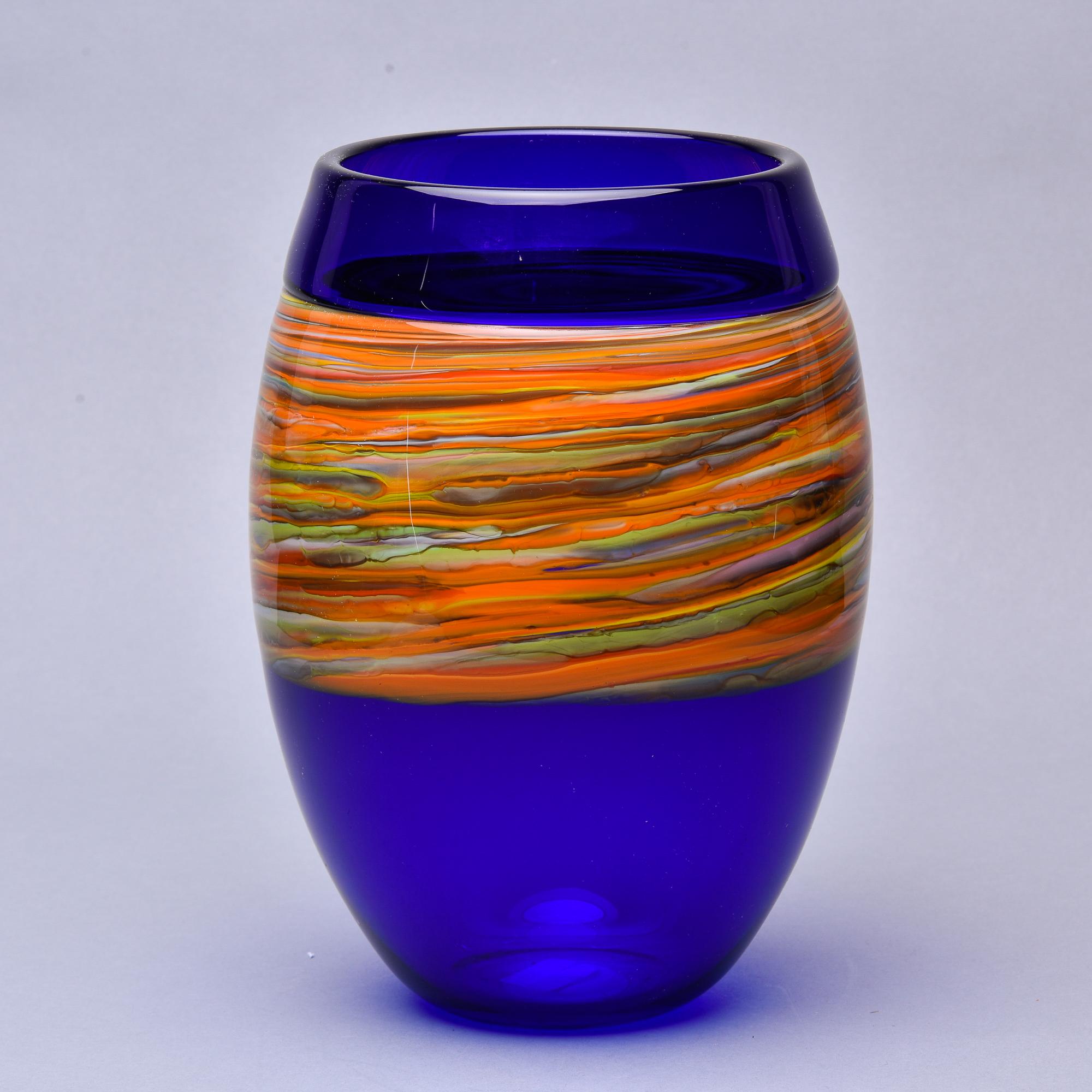 Found in Italy, this circa 1970s signed Cenedese Murano glass vase features a saturated cobalt blue body with a wide, streaky band of orange and yellow with accents of green and white. Substantial size - just under 12” tall. Etched Cenedese