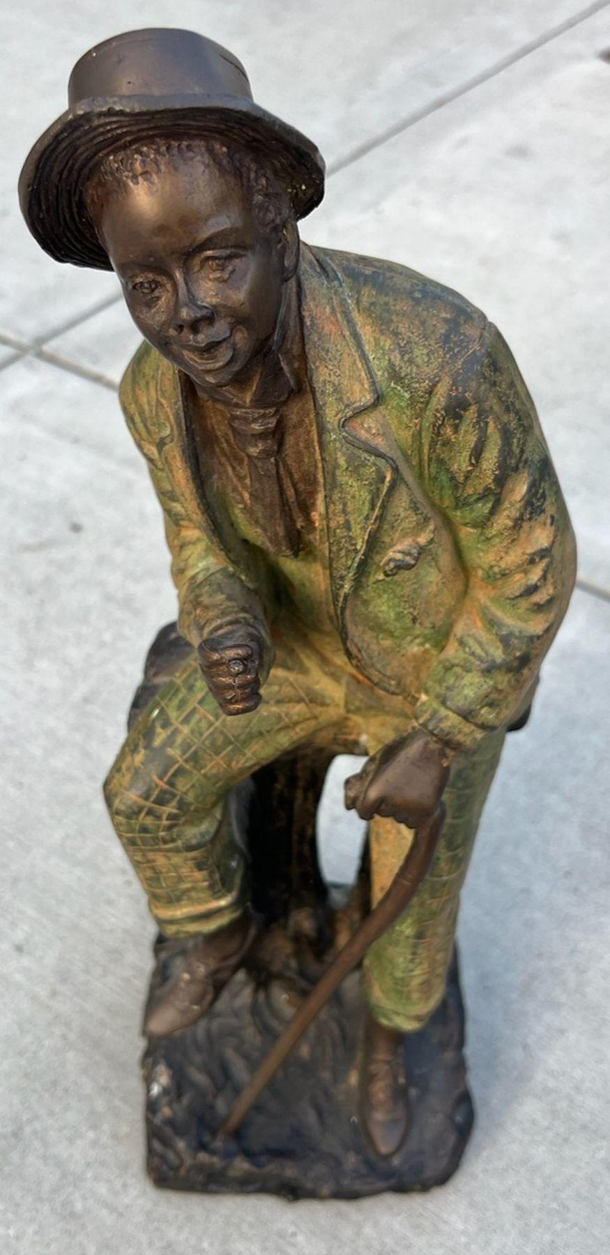 Grande scultura in bronzo di un gentiluomo meridionale con vernice originale. Questa scultura raffigura un uomo che fuma un sigaro seduto su un alto sgabello o una panchina con un bastone nell'altra mano. La vernice si è usurata nei punti di maggior