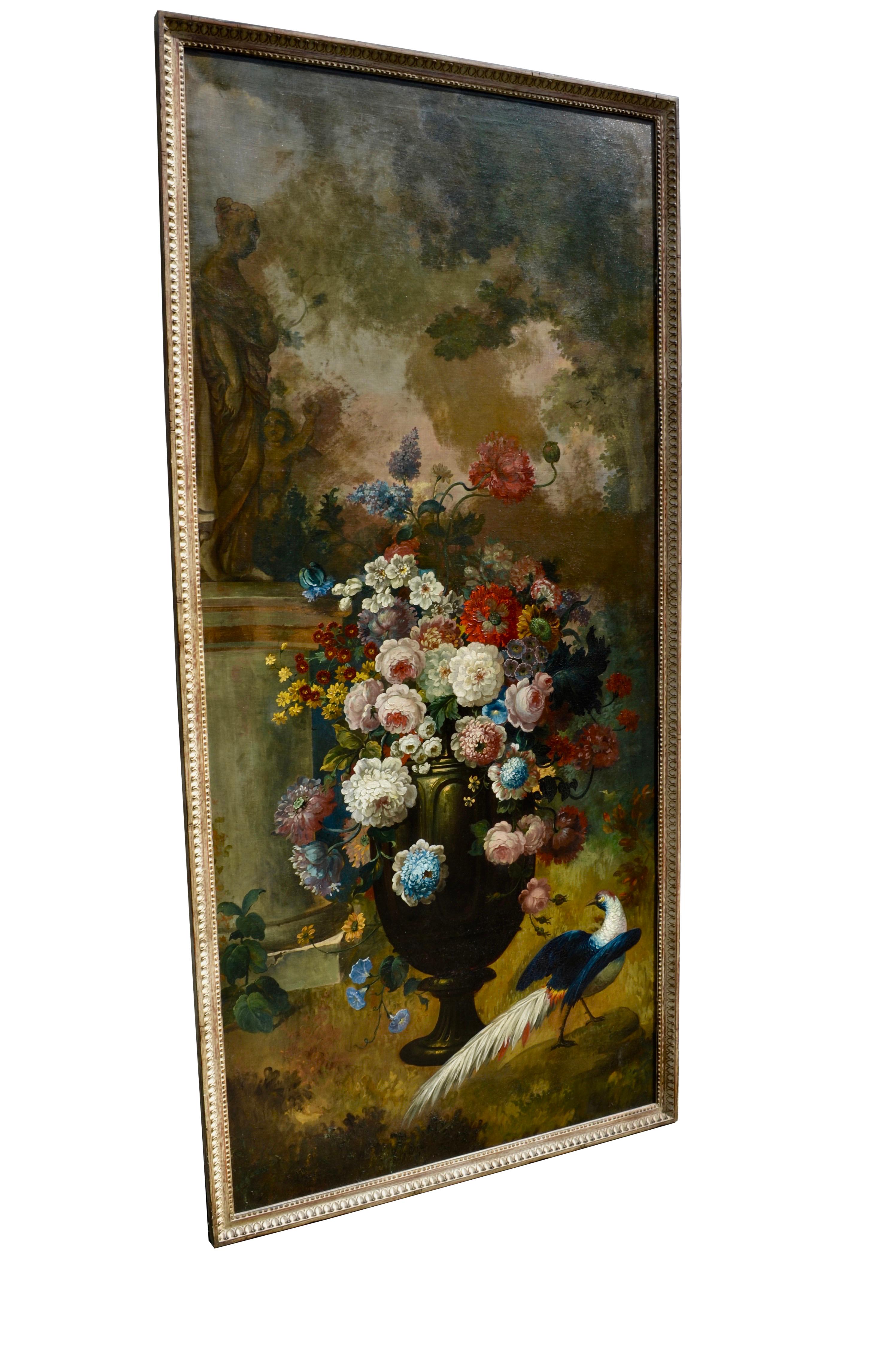 A tall impressive and very decorative oil painting on canvas depicting an arrangement of multi-coloured flowers in a classical urn. At the bottom of the urn is a peacock. The top left hand side of the painting shows a young classical maiden with a