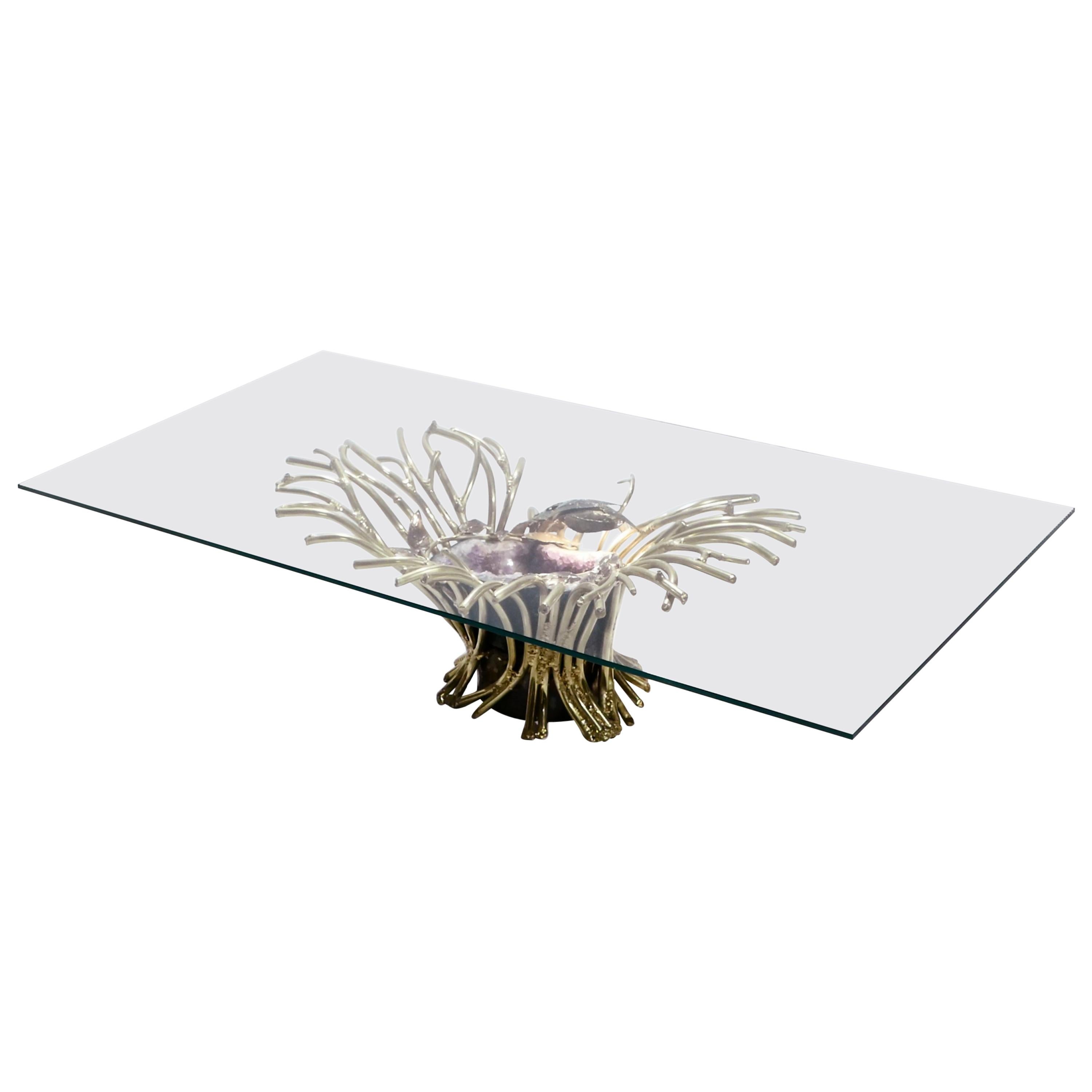 The creative design of this coffee table by Isabelle Faure is breathtaking. Tangled in a web of heavy brass “branches” is a monstrous amethyst geode, lit from the inside. This sculpture forms the base for a thick slab of transparent glass, a choice