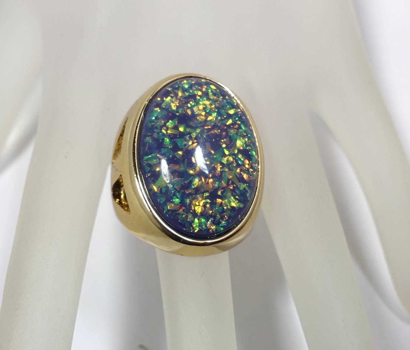 This large Kenneth Lane ring features a cabochon cut faux fire opal stone in a gold tone metal setting.  This ring is adjustable up to a size 7 and measures 1” x ¾” across the top.  In excellent condition, this ring is signed “Kenneth Lane”.