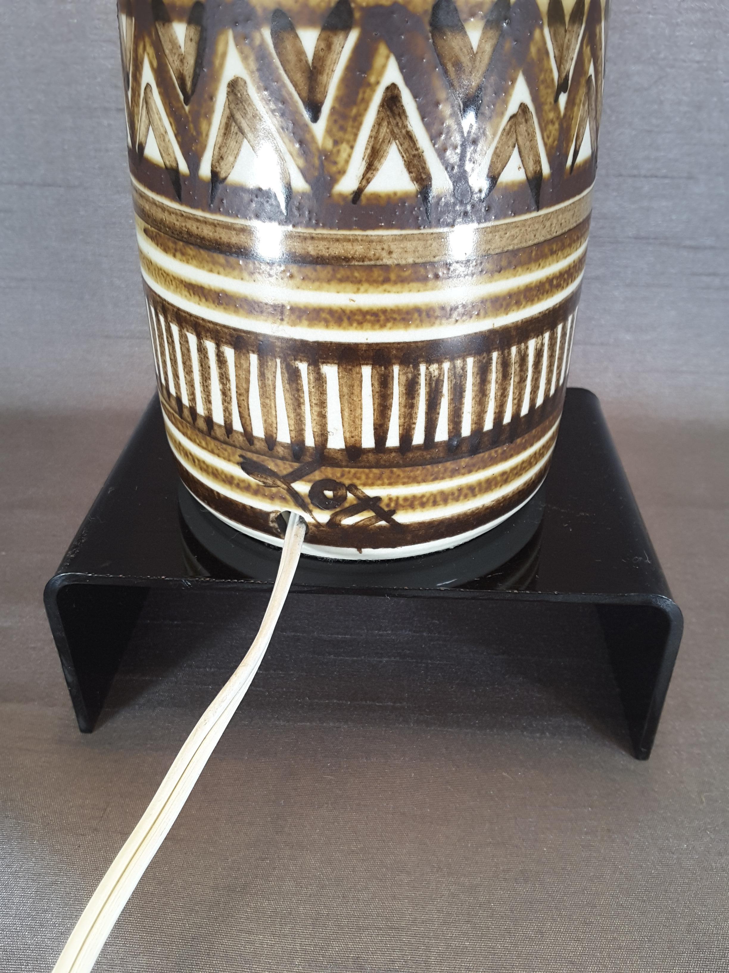 Large signed Lotte & Gunnar Bostlund table lamp, tribal pattern from the 1960s.
 The lamp is hand painted in geometric patterns on a glazed stoneware, Original shade, harp and finial. The base is signed on the side where the wire for the plug