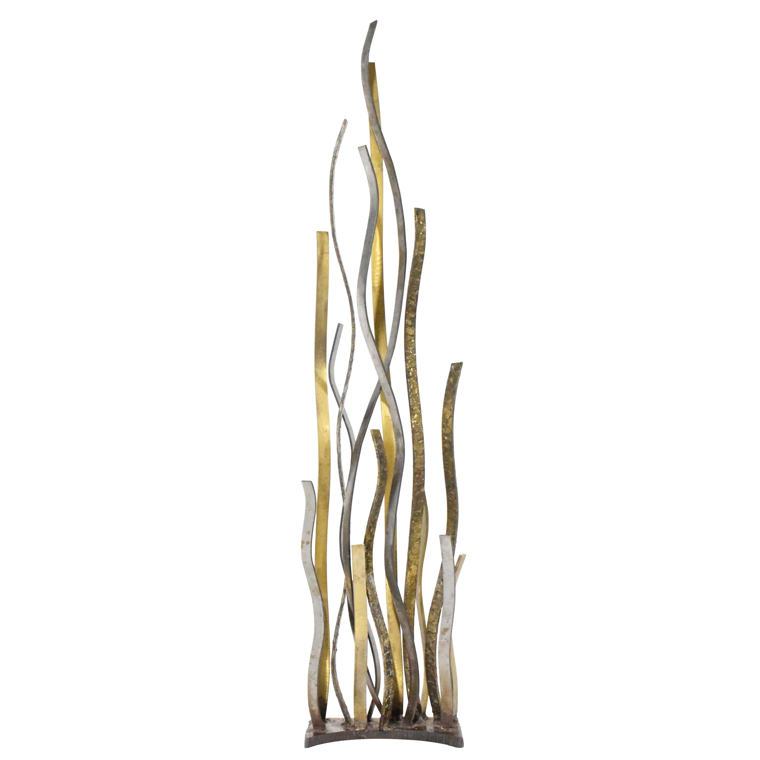 Very tall Silas Seandel mixed metal sculpture. In brass, bronze and steel. Abstract design that mimics tall grass or flames with a wavy effect. Incised to base 