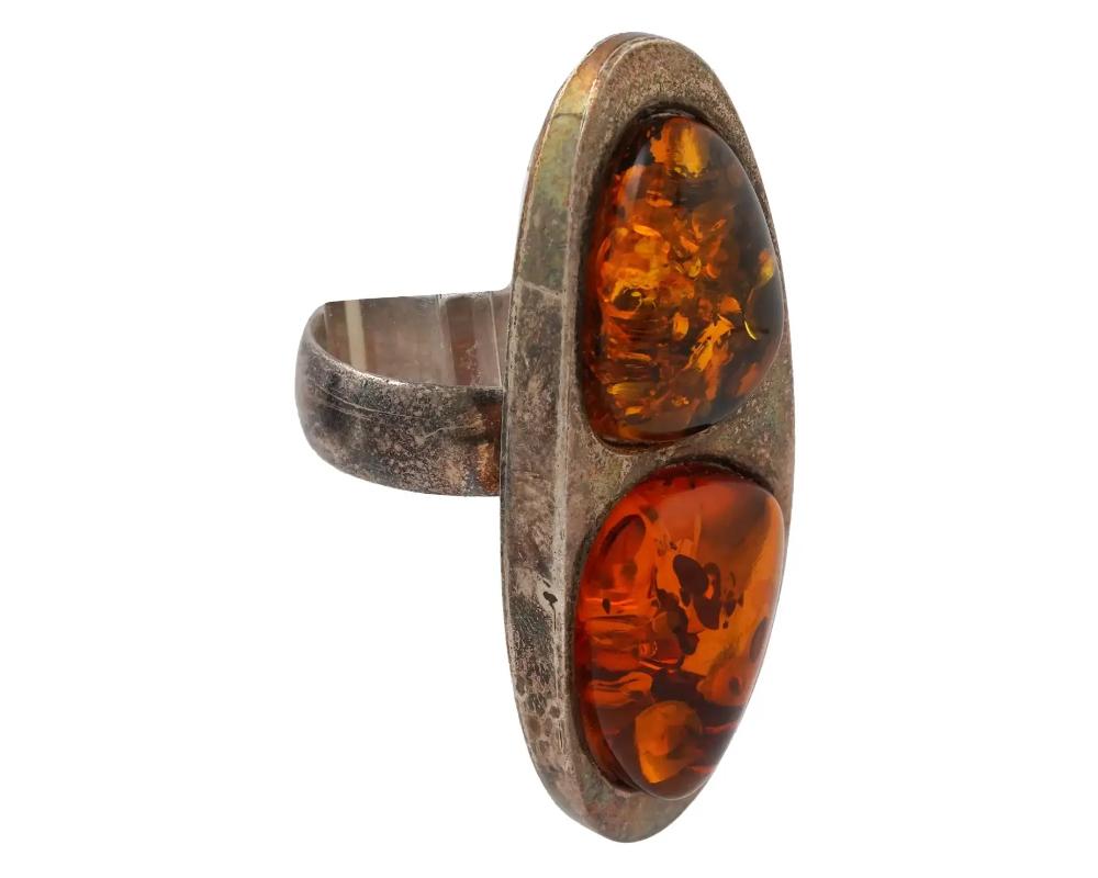 A large Modern elongated shaped Silver jewelry cocktail ring. the ring is encrusted with two natural Baltic Amber stones. Unmarked. Circa: Mid 20th century. Total weight: 12 g. Vintage and Modern Silver and Natural Stones Jewelry Wares and