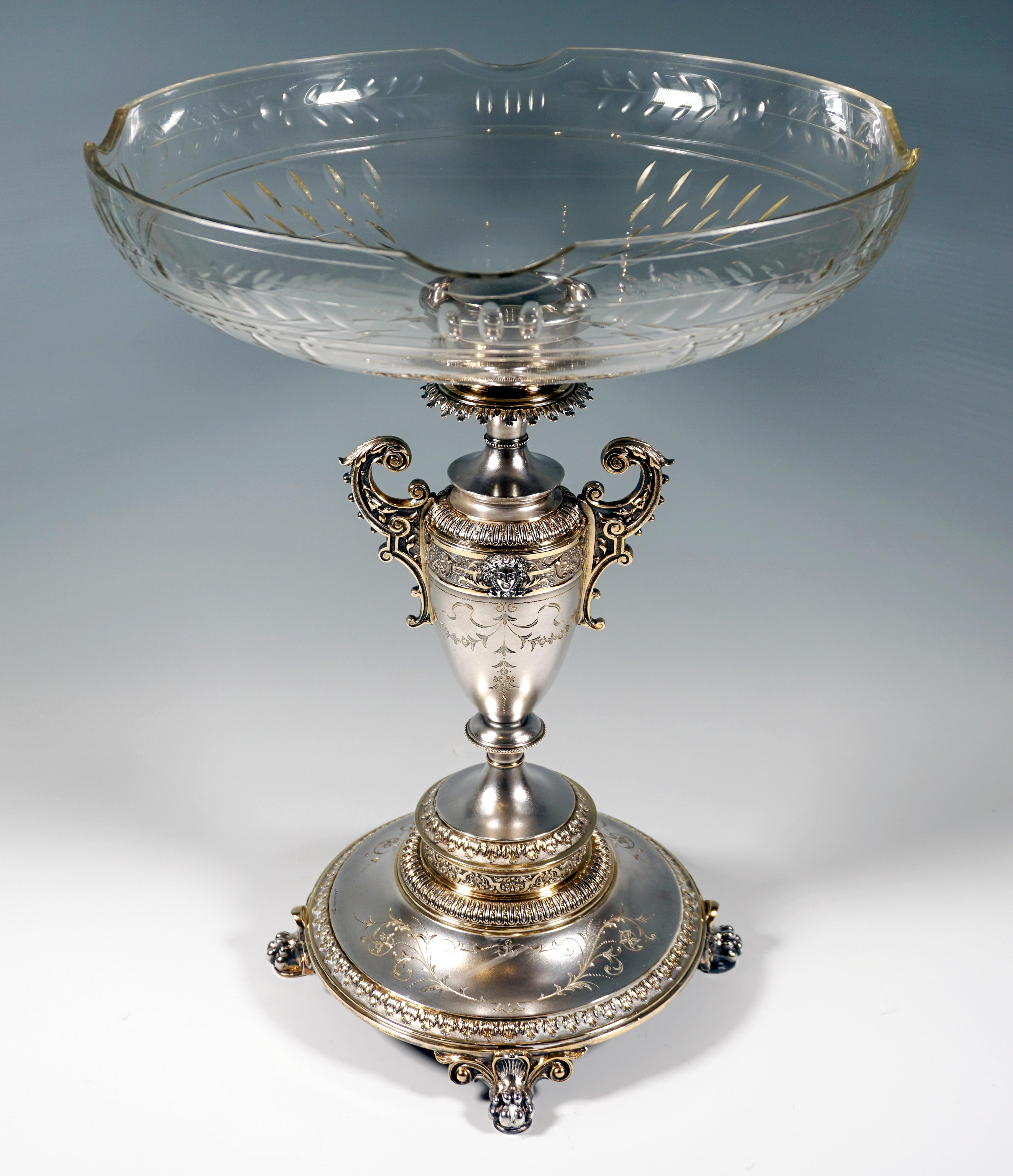 Large festive silver centerpiece on a wide foot, supported by four feet with double lion paws and volute decoration, the lower edge bordered by a surrounding band with chased acanthus leaf decoration, slightly fluted central zone of the foot with