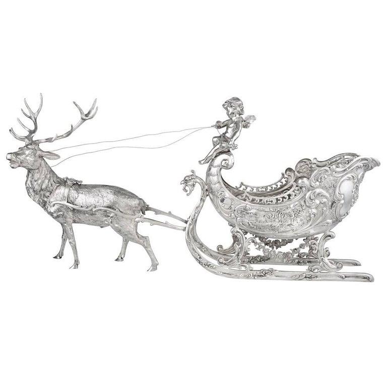Christmas reindeer and sleigh sculpture in sterling silver, depicting a cherub driving an ornate sleigh pulled by a beautifully hand-chased reindeer. The sleigh measuring approximately 19.5