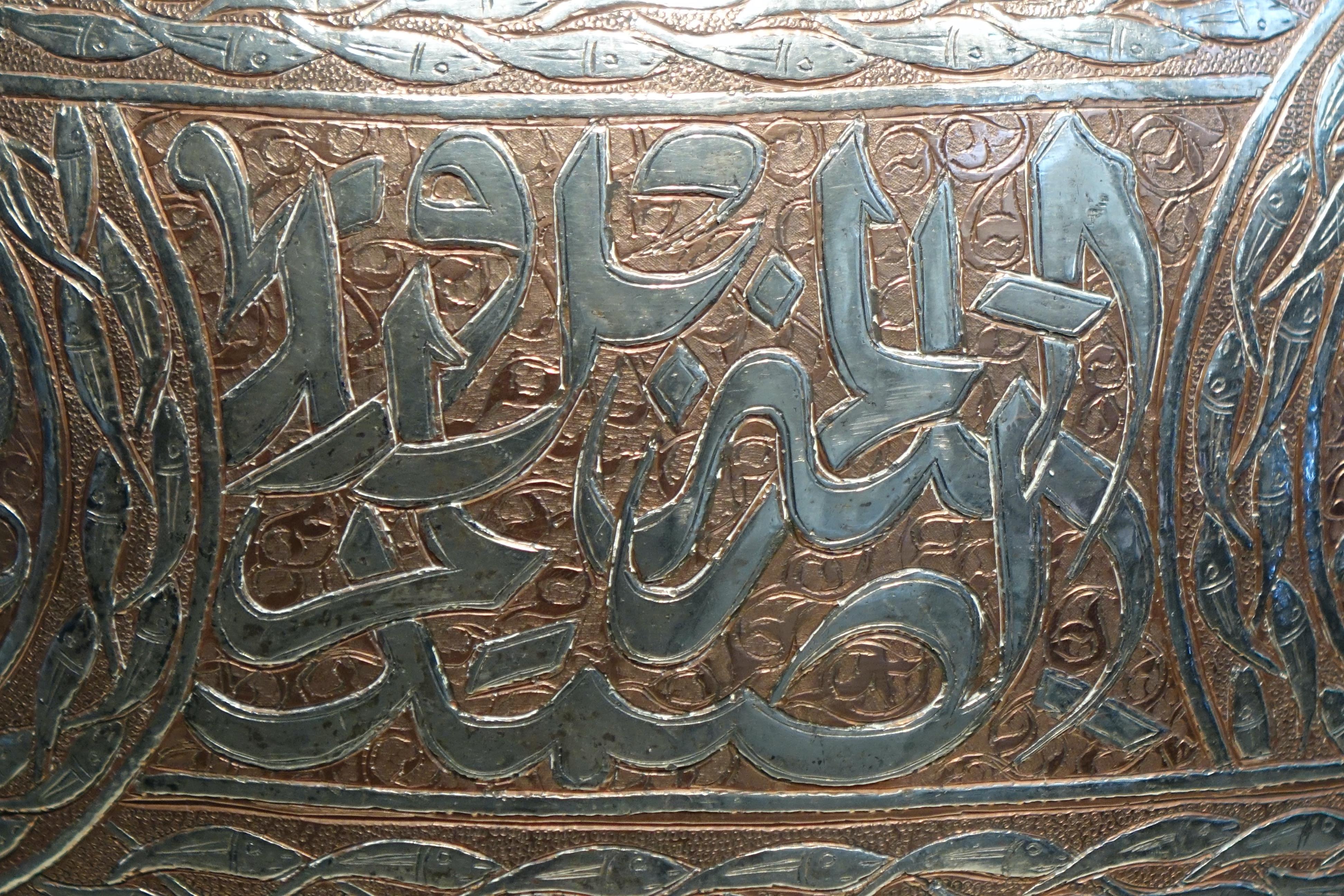 
Grande vaso in rame damascato in argento, decorato con volute di fogliame e animali (pesci, gatti, antilopi, gazzelle) che racchiude quattro cartucce da scrittura thuluth.
Due registri di iscrizioni compongono la parte inferiore del vaso.
Siria o