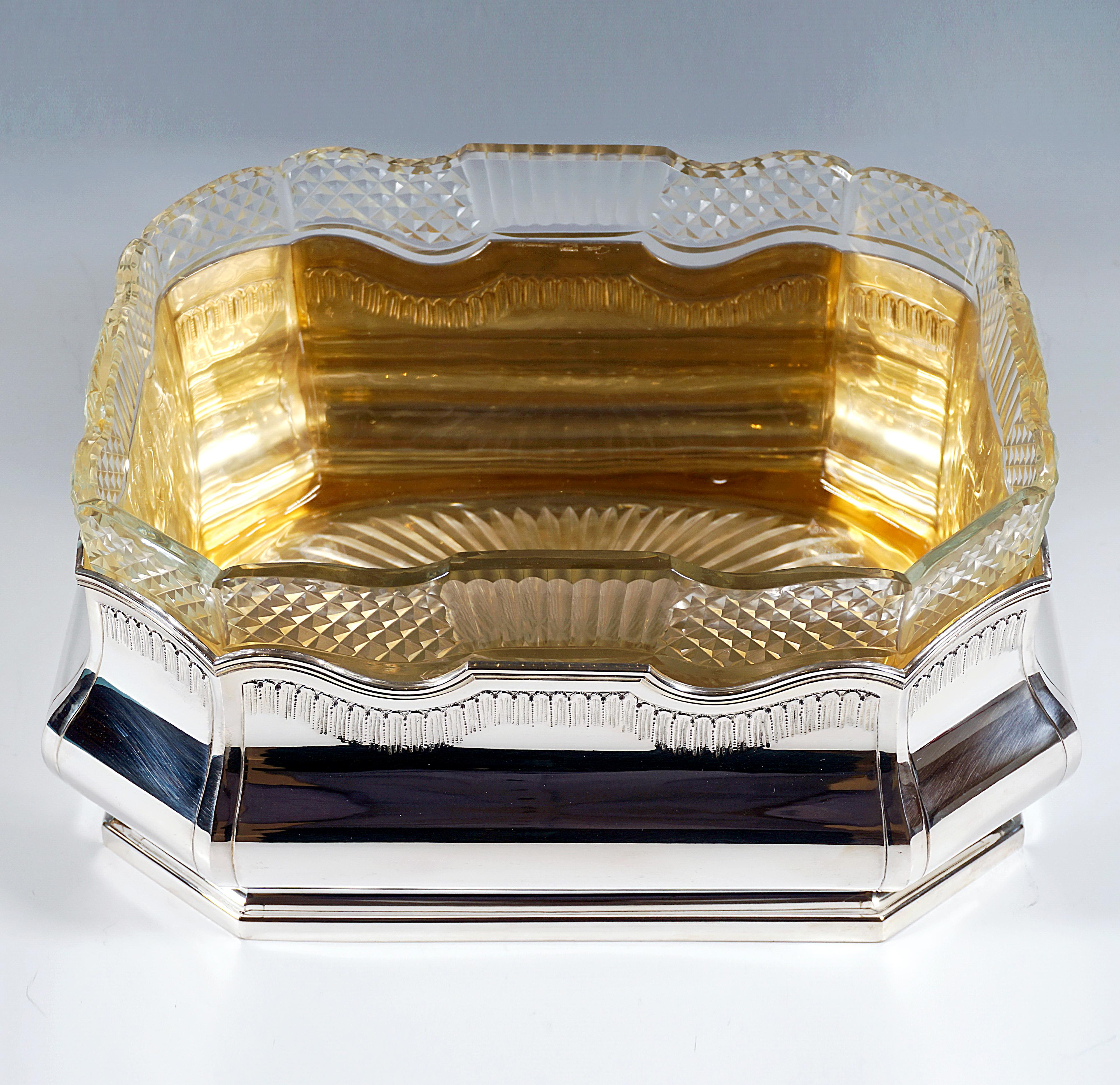 Large silver vessel with an elongated octagonal ground plan on a stepped, slightly recessed stand, bulbous, smooth walls with surrounding grooves and canopy-like decoration on the upper edge of the panels, rhythmic, partly wavy cut finish with