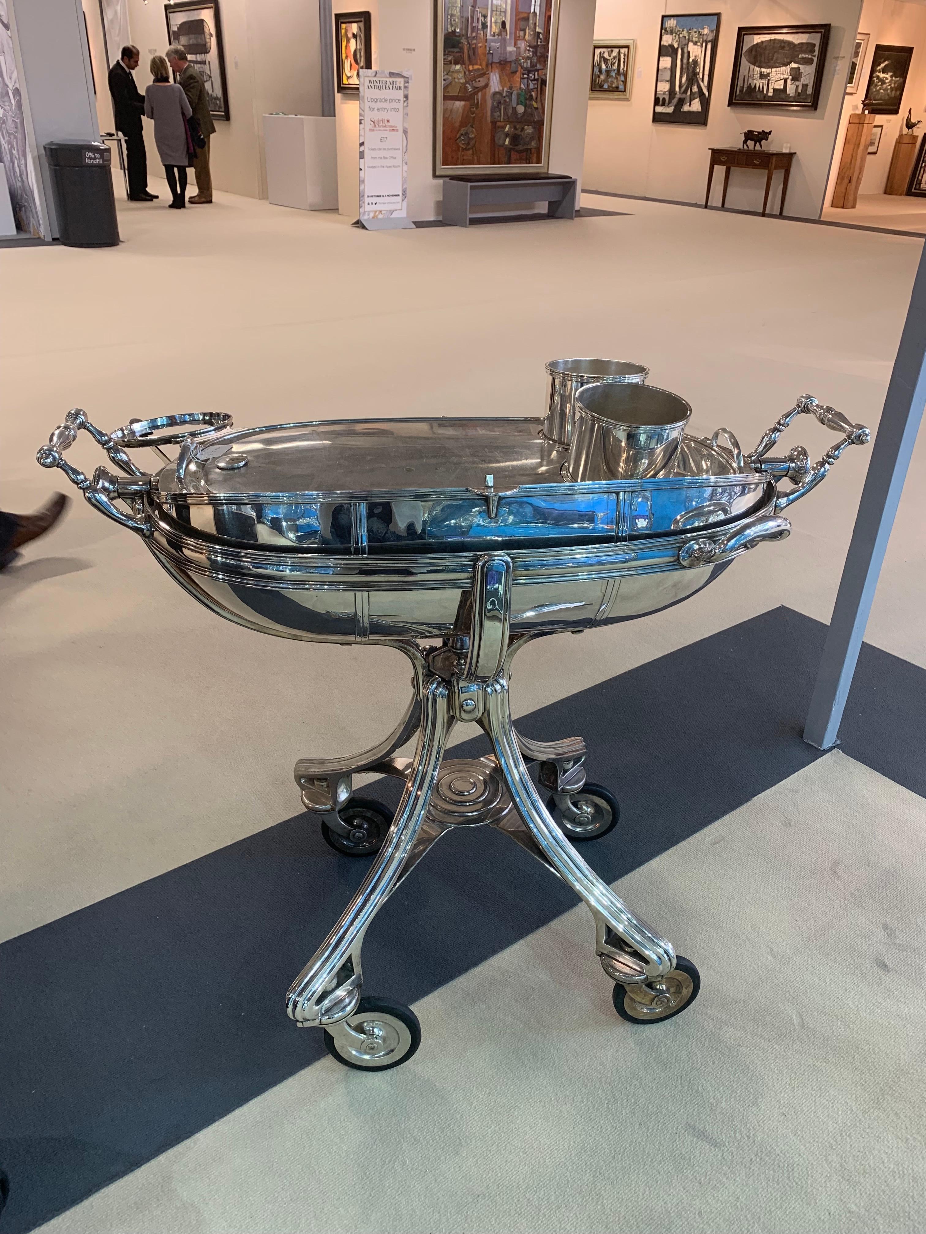 A large Silver plate carving trolley or Roast Beef trolley on four wheels with a hinged lid which opens to the hot water plate and two compartments inside for accompaniments such as vegetables and gravy. There is also an interior shelf for carving