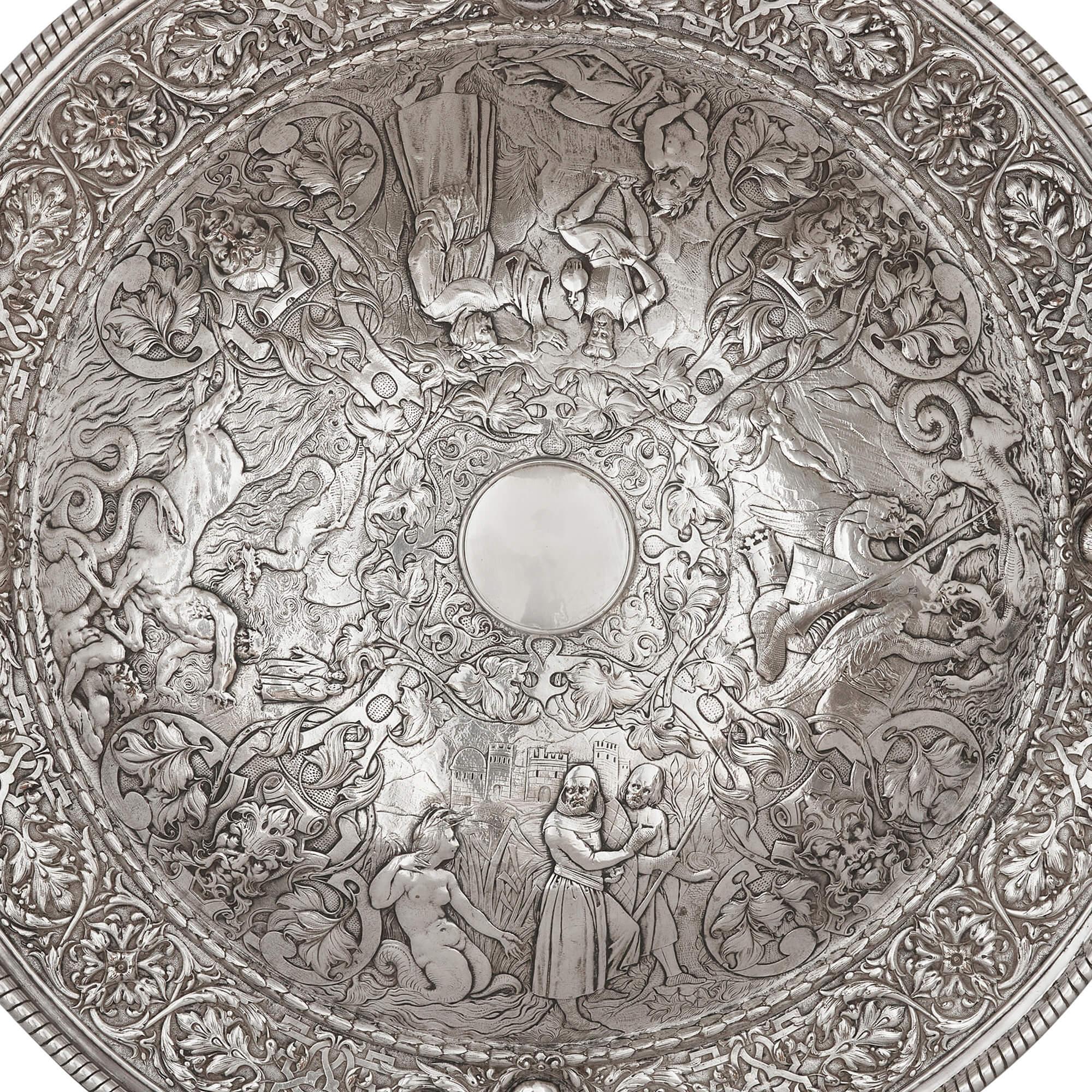Large silver plated charger with mythological and battle scenes 
English, 19th century 
Height 4cm, diameter 68cm

This silver plated charger depicts scenes of battle between humans and mythical creatures which surround the plain central