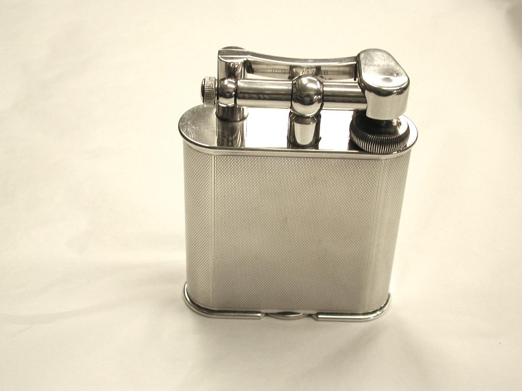 Engine-turned silver plated table lighter.
This table lighter is in superb condition and uses lighter fluid and a flint.
Made in the 1930s by the leading manufacturers and retailers Alfred Dunhill of Jermyn Street, London.