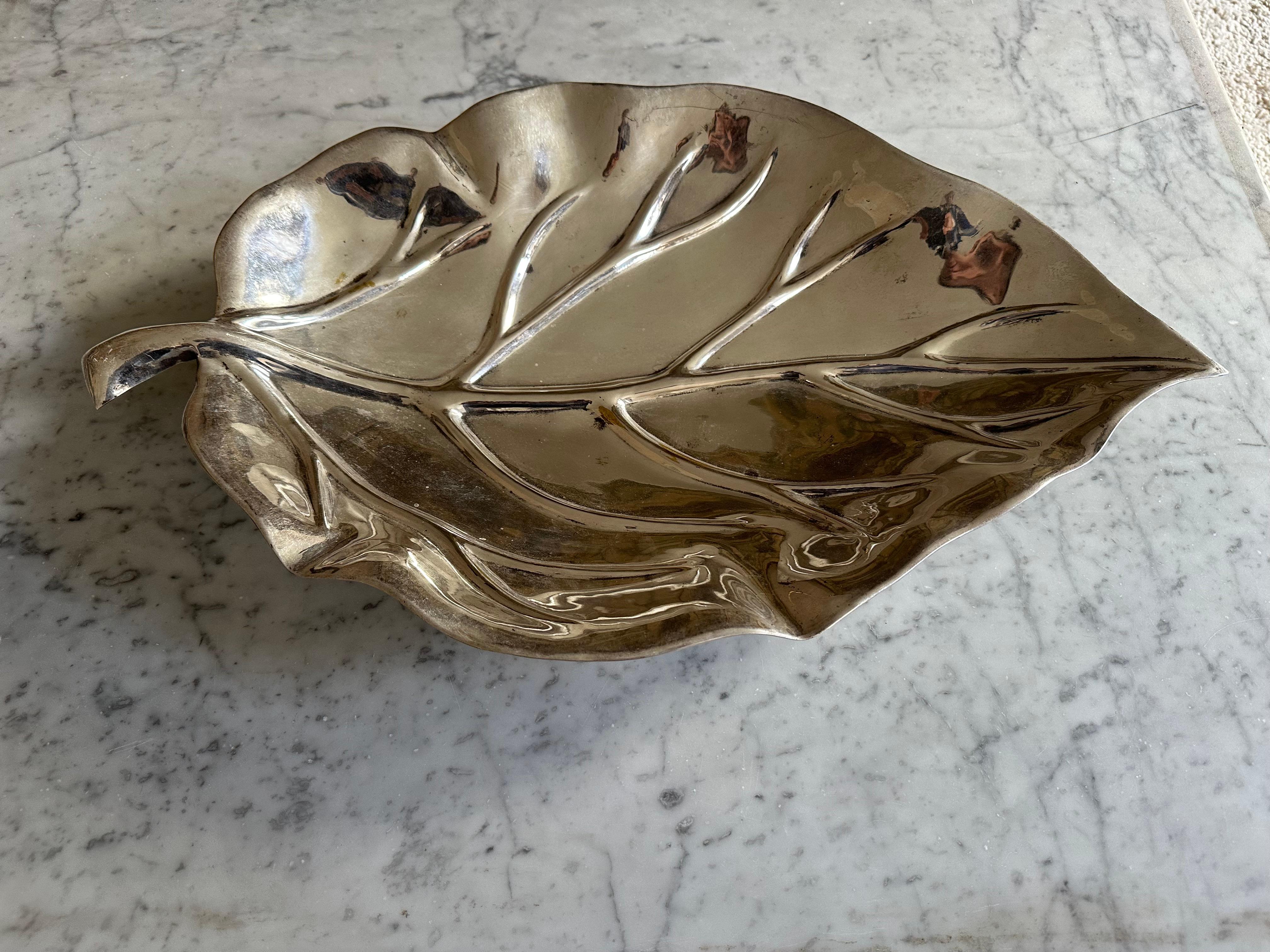 Découvrez le charme du design vintage avec ce grand bol argenté en forme de feuille de Valenti, fabriqué dans les années 1970. Ce bol décoratif repose sur des pieds sphériques, alliant élégance et fonctionnalité.

Le placage argenté du bol s'est usé
