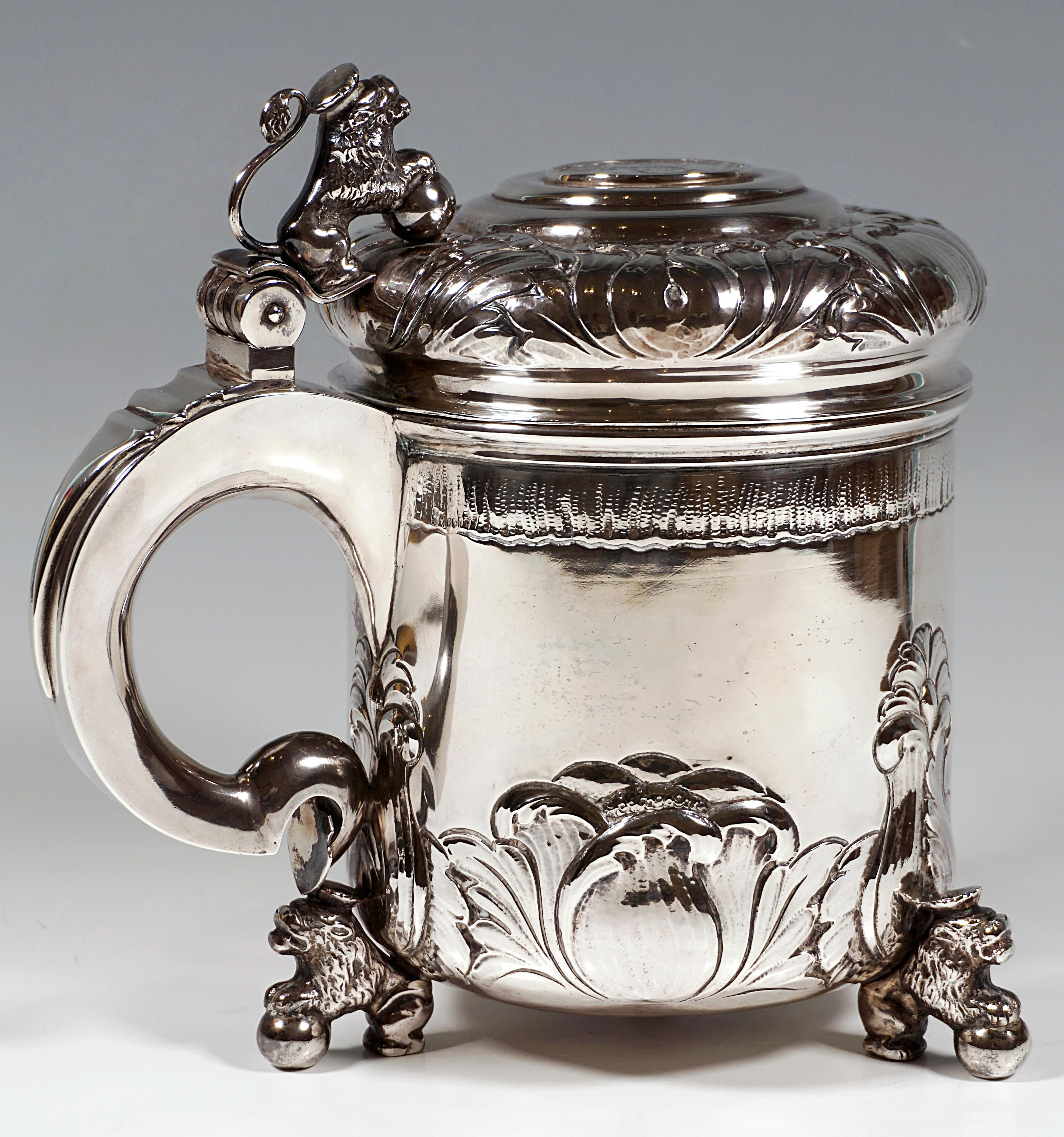 A large silver tankard of basic cylindrical form, standing on three feet in the shape of seated crowned lions with their forelegs resting on spheres, floral relief decoration to the lower part of the vessel and to the domed loaf-shaped lid, which is