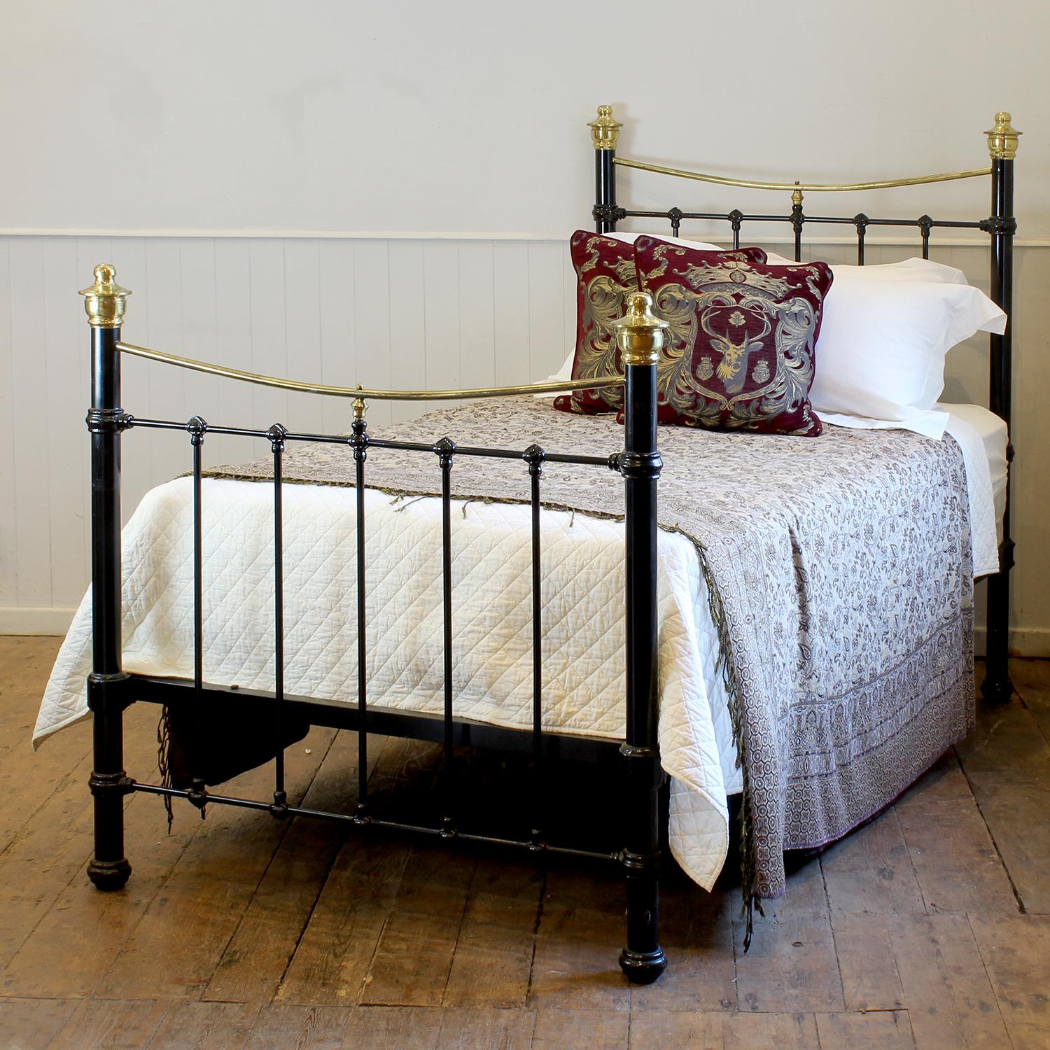 A striking example of early 20th-century craftsmanship, this antique bed dates to around 1900 and showcases a timeless elegance. Constructed from sturdy metal and painted a deep, classic black, the bed features gracefully curved brass top rails that