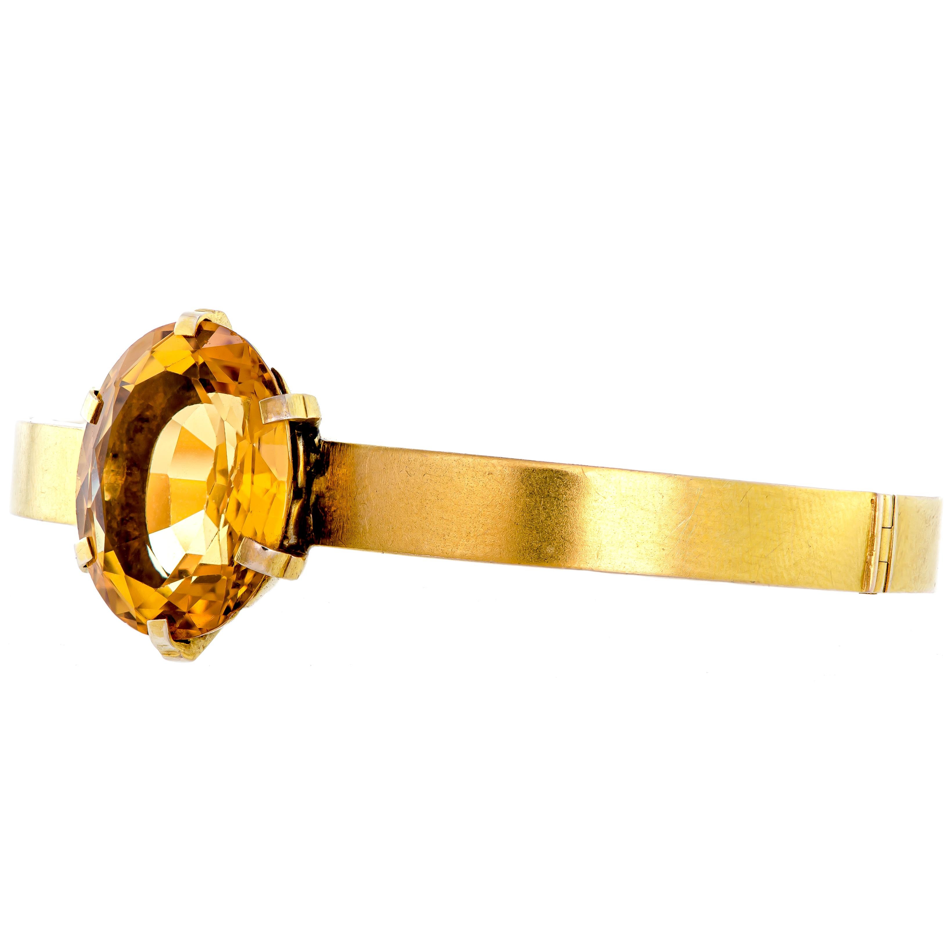 This striking sizeable faceted oval cut citrine bracelet is unique. This stiff-hinged bracelet is crafted out of 14kt yellow gold. It features one faceted oval cut citrine that measures 20.4 x 15.5 x 9.6mm (approximate) with an estimated weight of