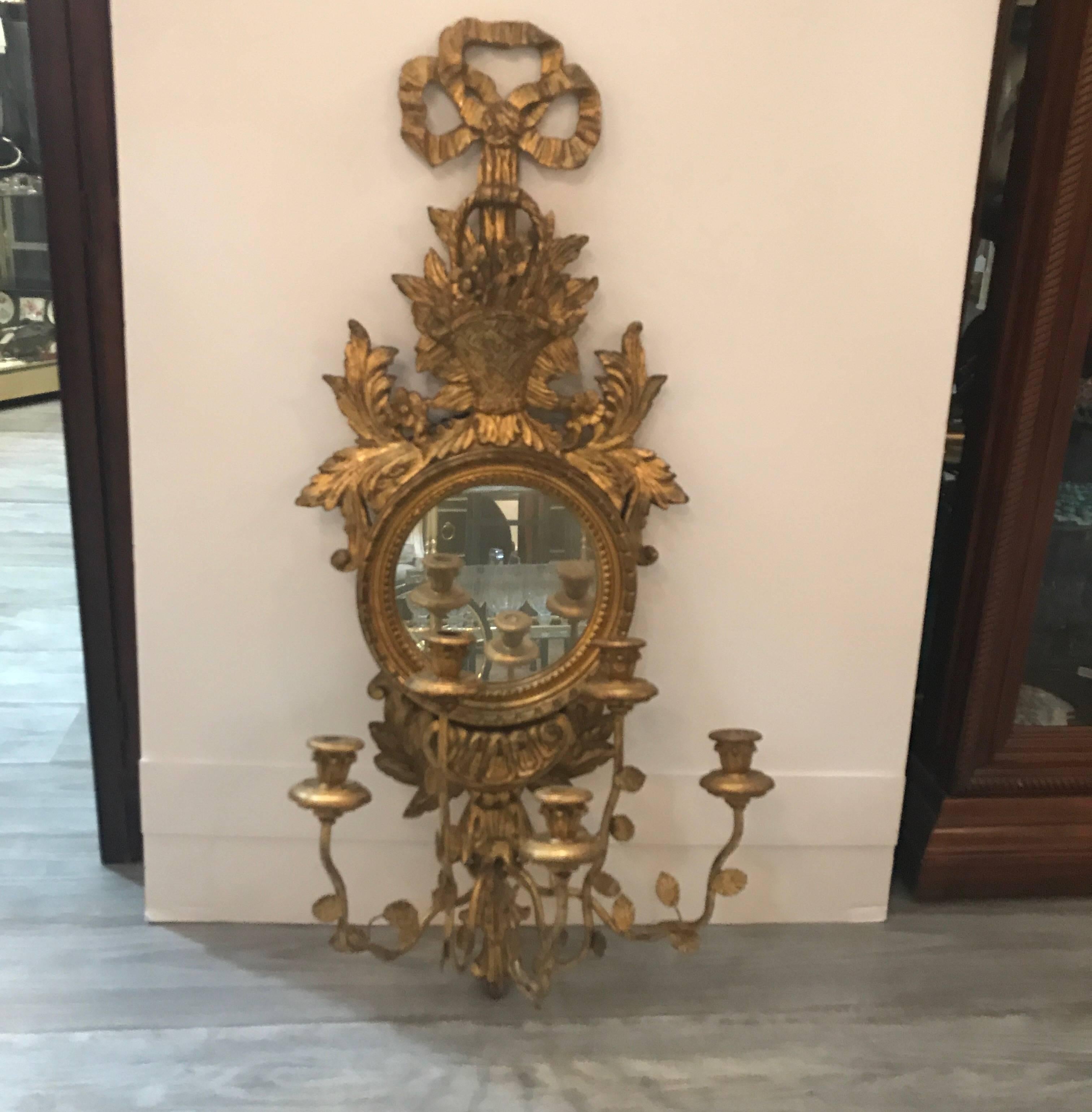 Elaborate carved giltwood and metal mirrored sconce. The all giltwood back with Centro round mirror with front girangole candleholder that is removable. Made in Italy, circa 1950. This item can be shipped UPS or Fedex at a considerable savings..