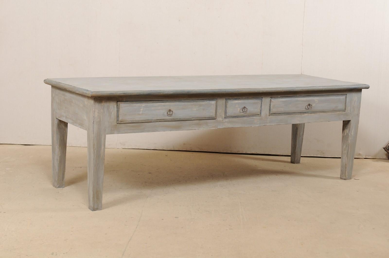 A large-sized American custom kitchen island table with drawers. This impressive table has been fashioned from old reclaimed wood and features a rectangular-shaped top, over a thick clean-lined apron which houses three-drawers along one side, and is