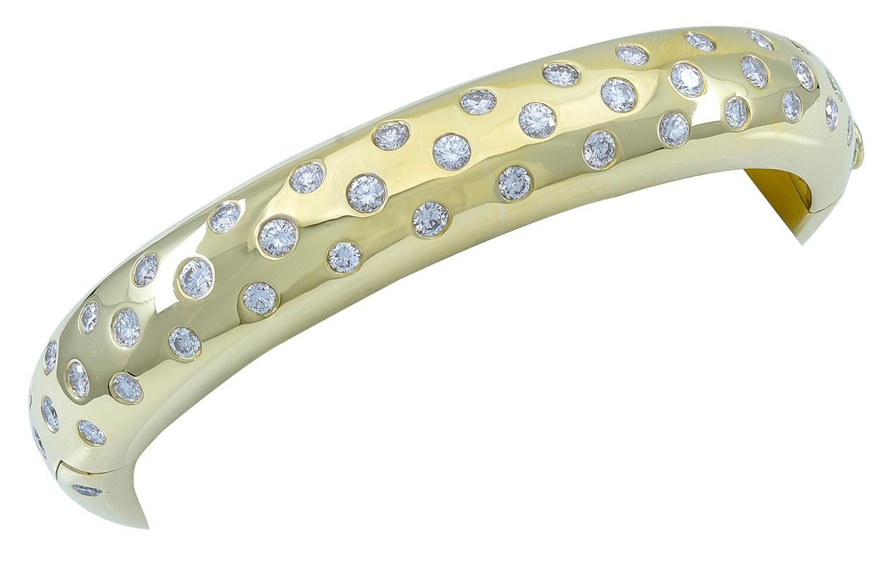 Fabulous bangle bracelet.  Very heavy gauge 18K yellow gold.  Encrusted all around,  with over nine carats of brilliant white diamonds.  For a large wrist. Hinge closure,  with an oval shape that wraps around and hugs the wrist.  2 1/3