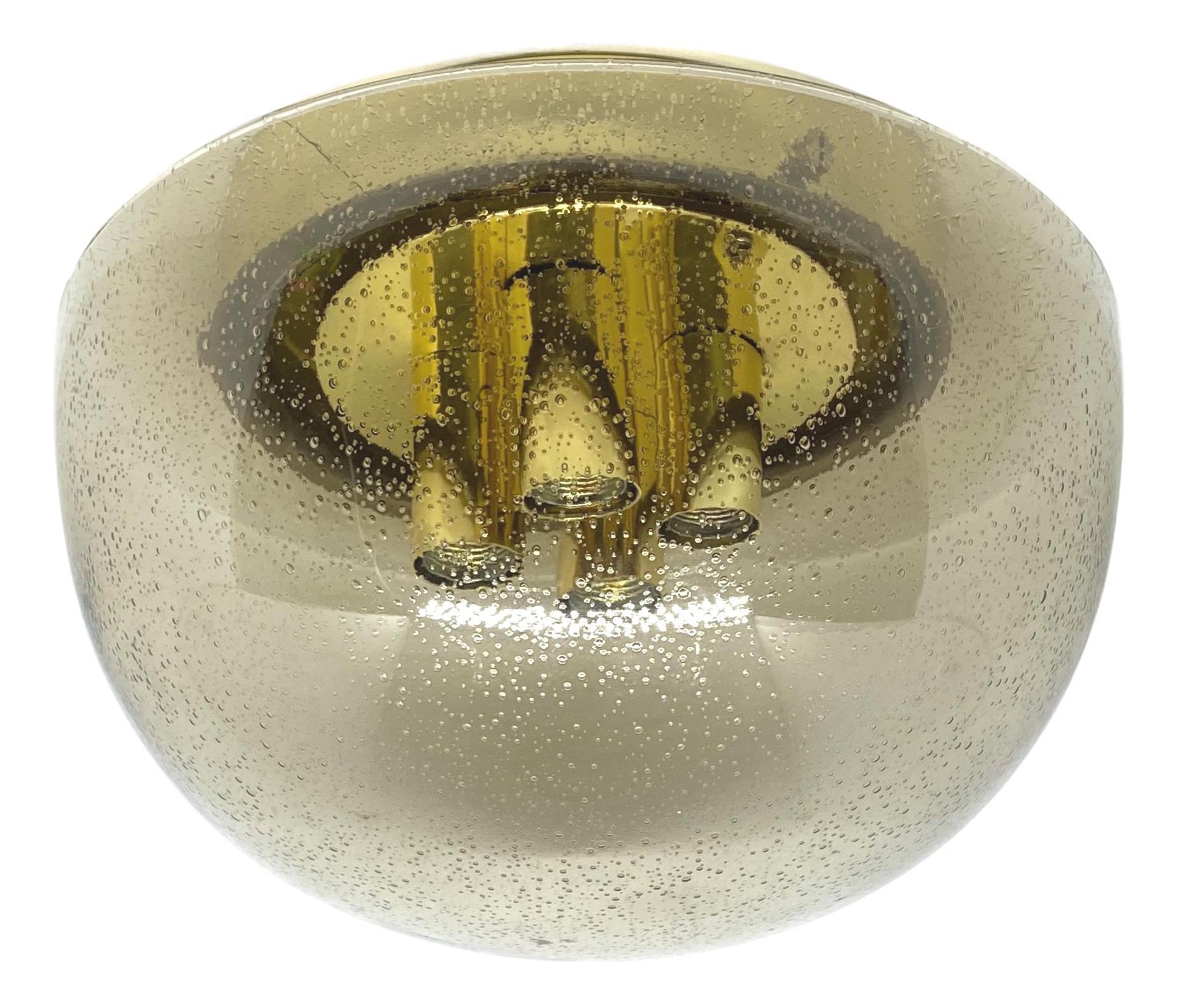 A beautiful large flush mount by German manufacturer Glashuette Limburg. The large bubble glass element is supported by a polished brass plate with four light sources. Beautiful bubble glass on a metal fixture. The fixture requires four European E14