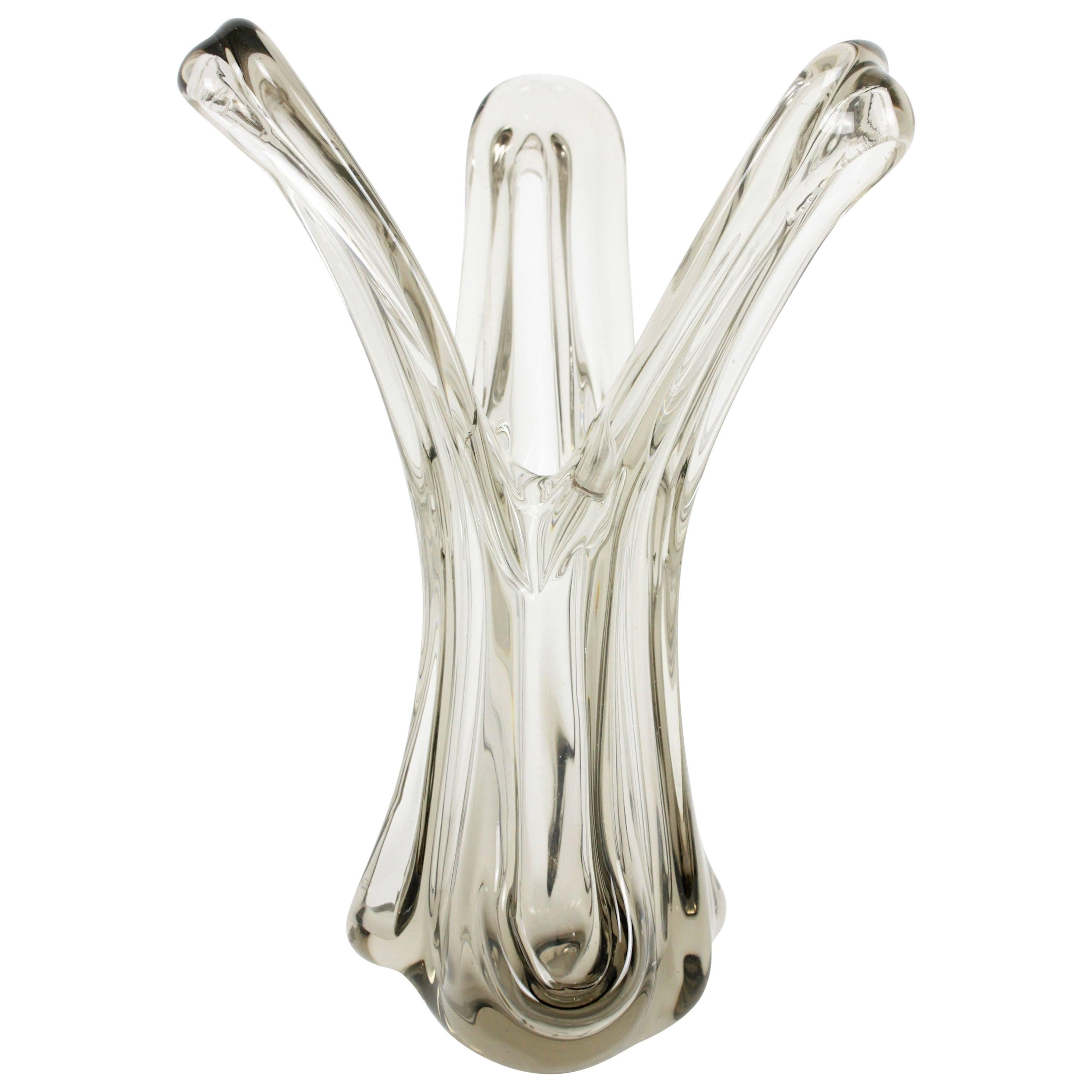 Eine skulpturale mundgeblasene offene Vase aus italienischem Murano-Glas in Klar- und Rauchglas. Italien, 1960er Jahre.
Das organische Design mit seinen gewundenen Formen ist sehr dekorativ. 
Wunderschön als dekoratives Mittelstück oder als Vase