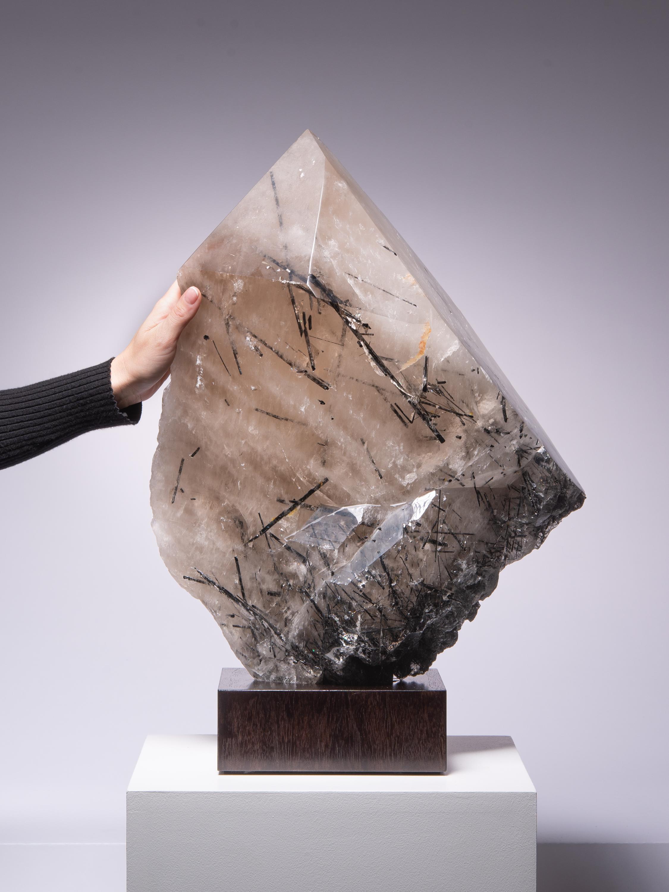 An impressive, large single crystal point of smoky quartz with pleasing facets. The interior of the quartz crystal is interspersed with gorgeous black tourmaline in a variety of orientations. A wonderful aesthetic and decorative piece.

This piece