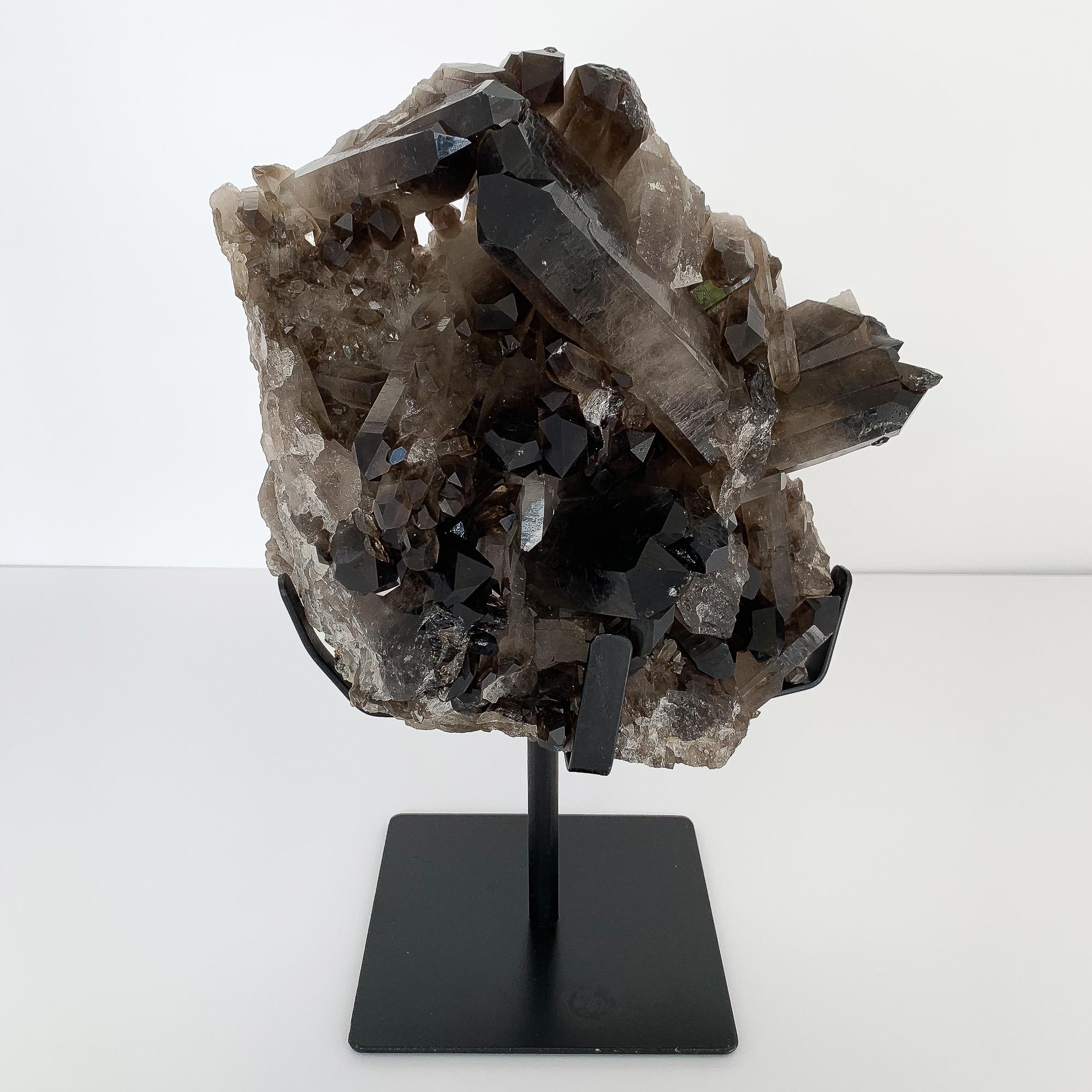 Large natural smoky quartz crystal specimen mounted to a pronged painted black metal Stand. 14