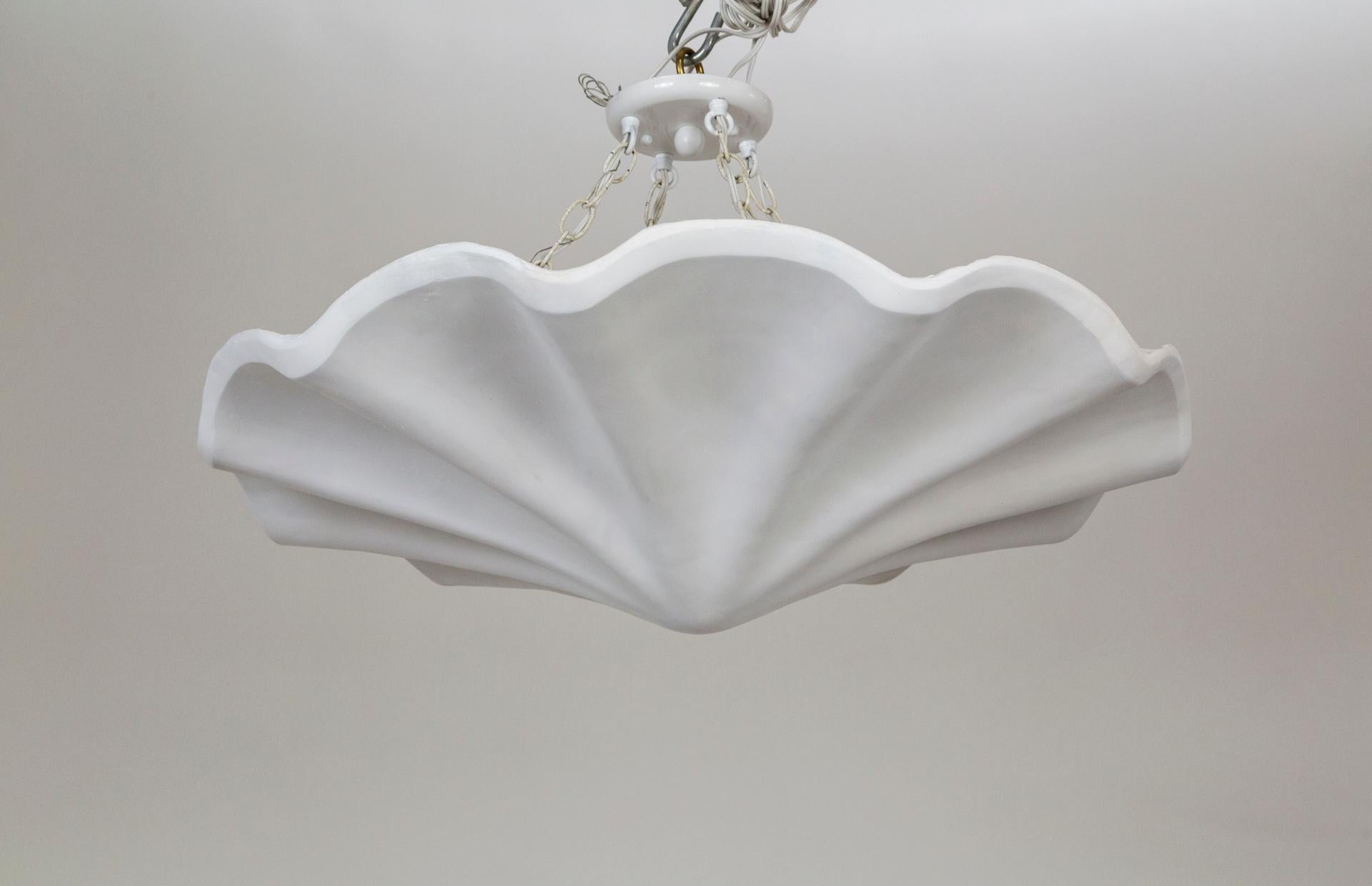 A plaster pendant in a smooth, undulating shell shape, with scalloped edges. A newer take on Francis Elkins's 1940s plaster plafonnier. Hanging by four white chains; with 4 medium base ceramic sockets. Contemporary; made from an original mold. We