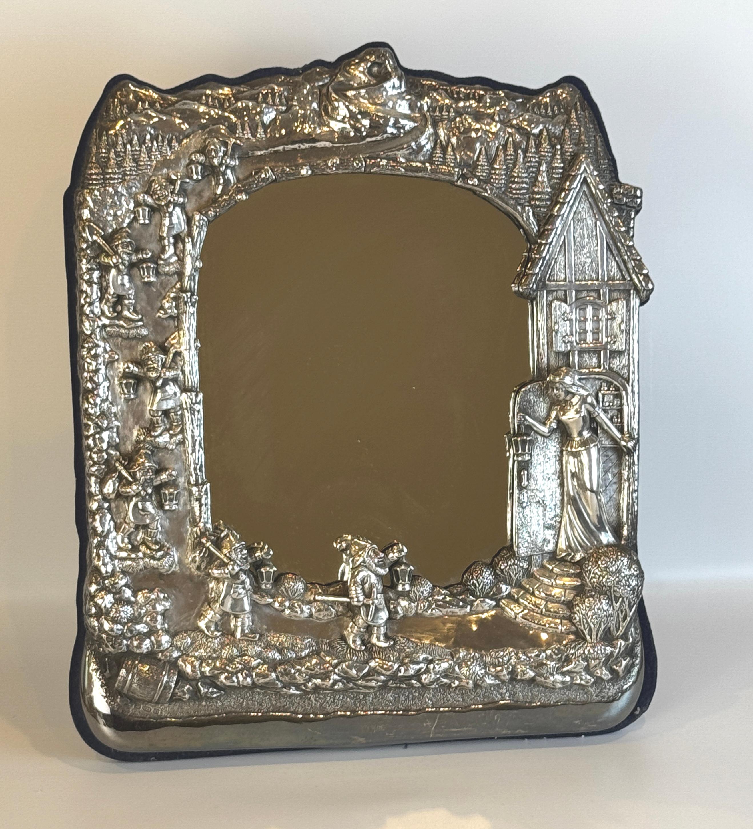 Grand miroir de table en argent sterling représentant Blanche-Neige et les sept nains. Le cadre est décoré en repoussé d'une charmante scène montrant les nains traversant un paysage de montagne boisé après une journée de travail à la mine, et