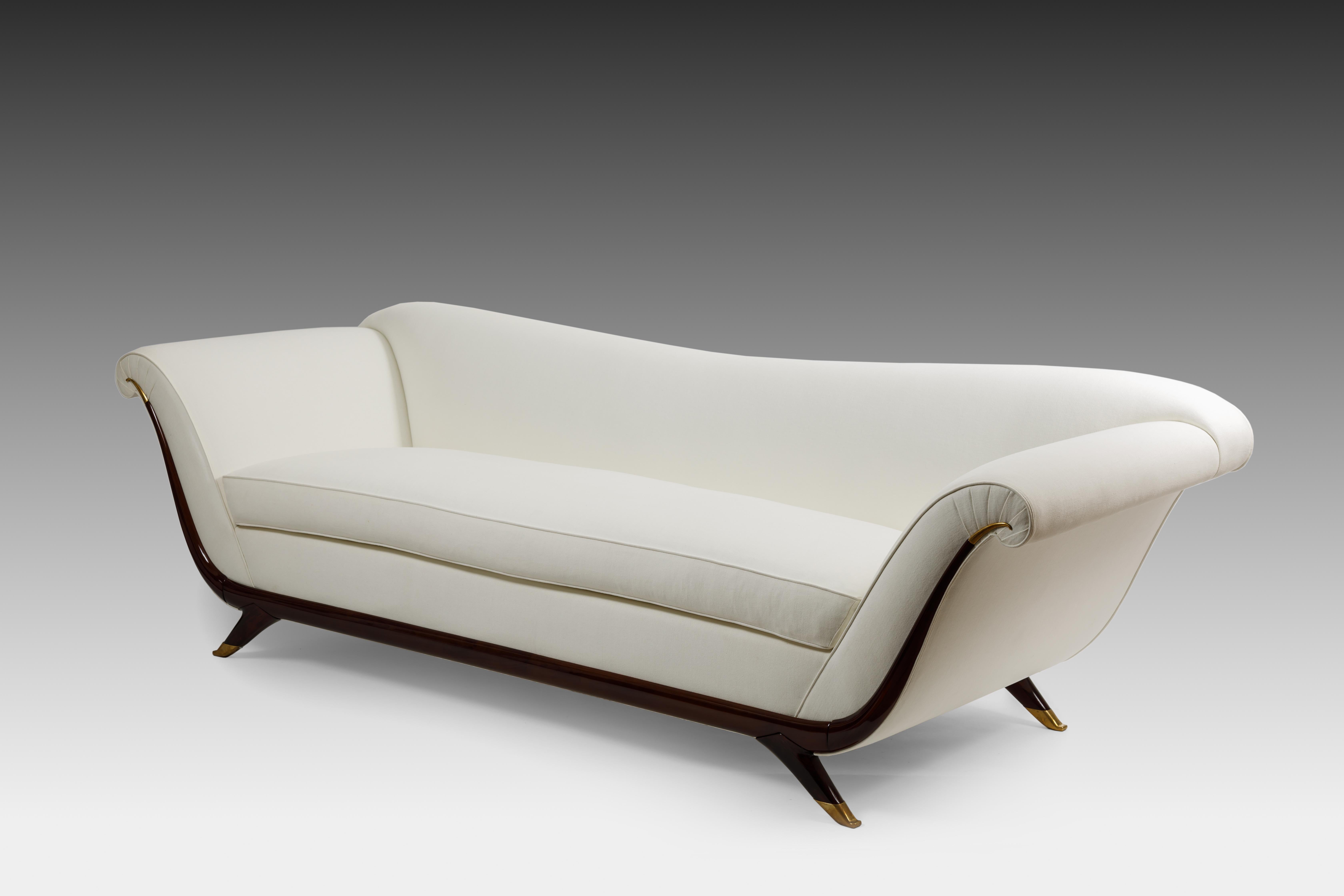 1940s Italian elegant long upholstered sofa with single seat cushion, lacquered wood and brass details, and splayed legs ending in brass sabots. This gondola-shaped sofa is contoured with sinuous lines in the scrolled arms, back and frame.
Fully