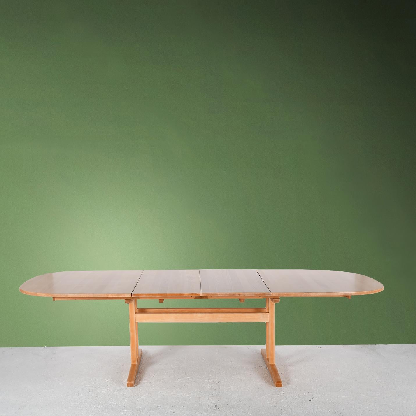 Solid beech oval table with two sliding tops and two extensions. This table comes from Denmark and was designed in the early 2000s. 
It has been completely sanded and protected with a satin varnish. The two extension leaves can be stored under the