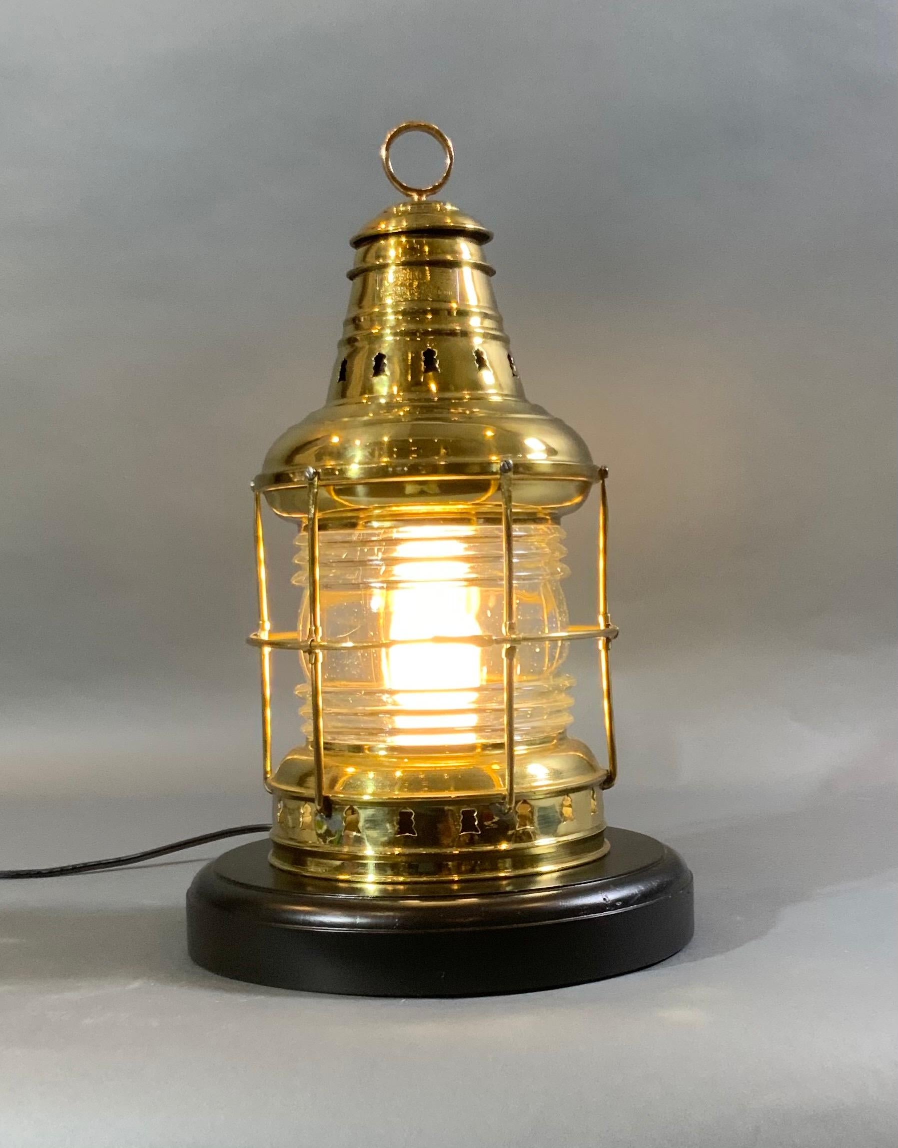 Ships anchor lantern by The Perkins Marine Lamp Company. With protective brass bars, vented top with hoisting ring. Lantern is mounted to a thick mahogany base. Lantern is wired with a new socket and cord for home use. Weight is 10 pounds.
