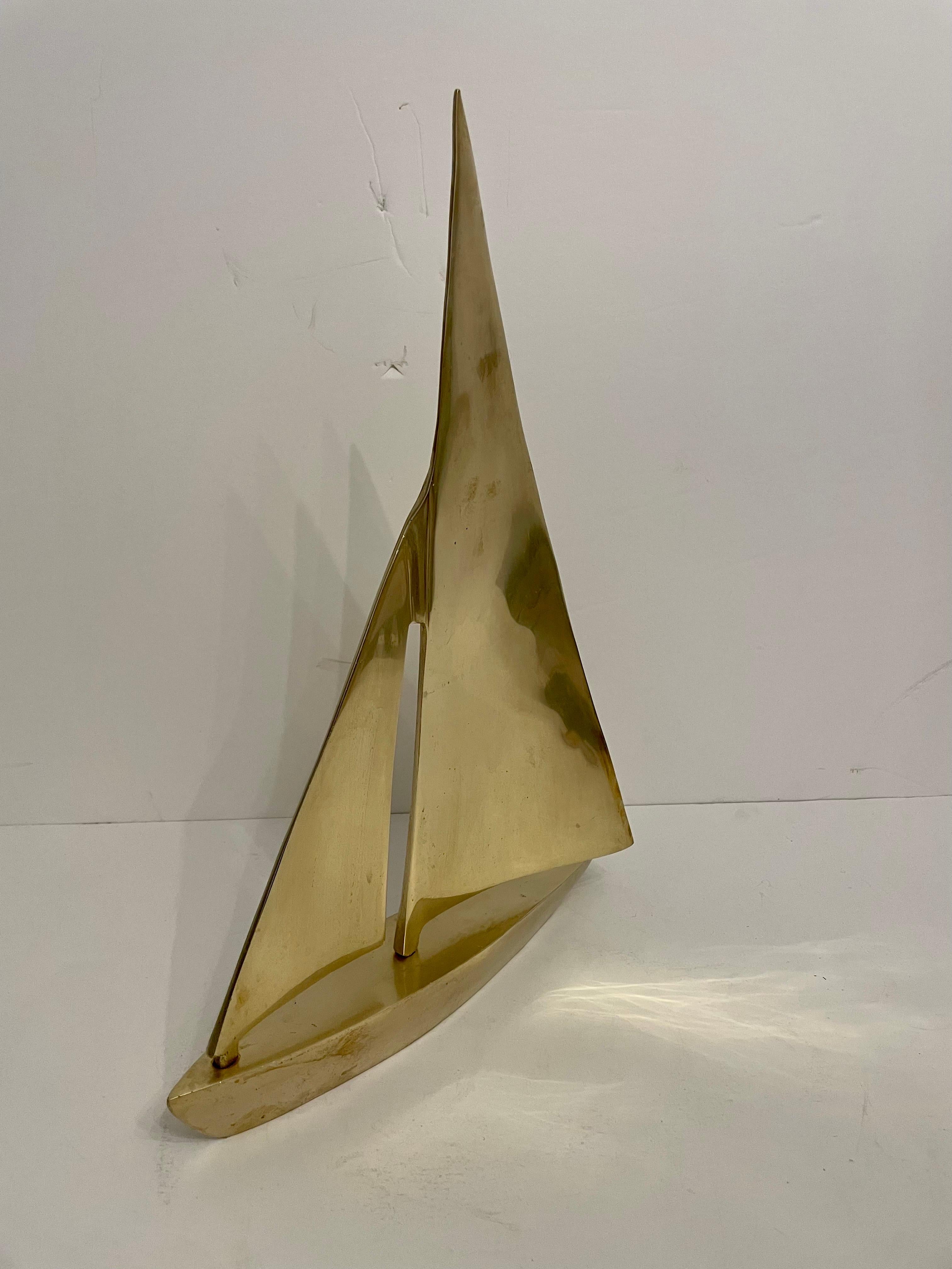 A very good quality decorative midcentury large solid brass sailboat on heavy brass base.  The brass finish lends a touch of opulence, enhancing the sculpture's aesthetic appeal and adding a warm, inviting ambiance to any space. A great  addition to