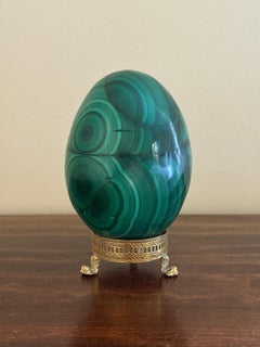 Gran huevo de malaquita maciza sobre soporte neoclásico de latón con patas de garra